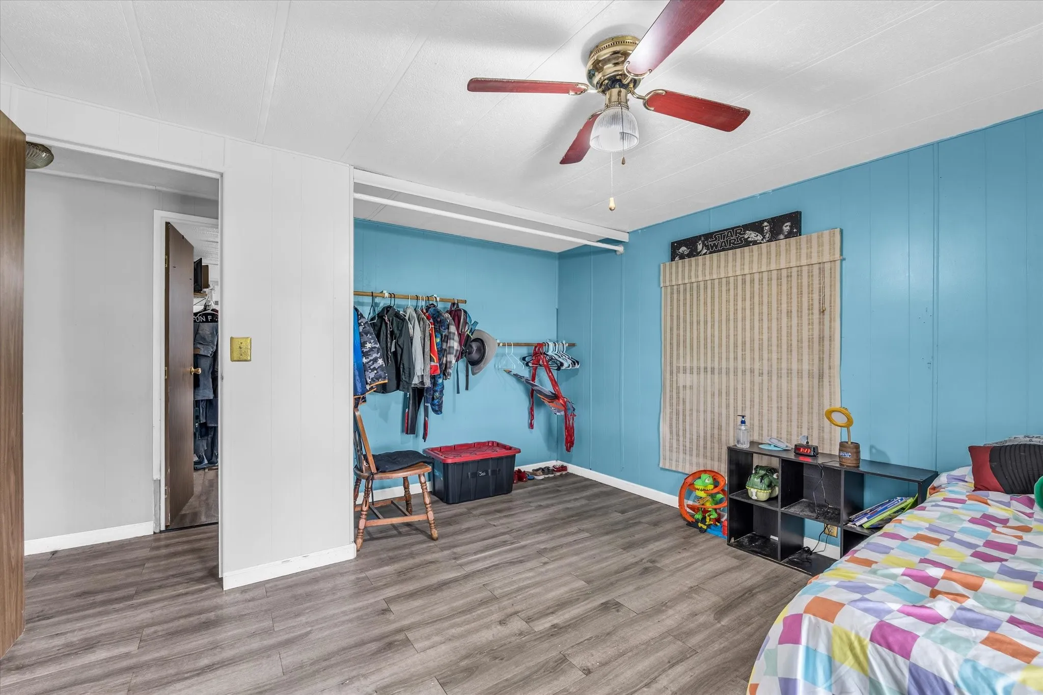 Wood-finish flooring with a ceiling fan light fixture and a window
