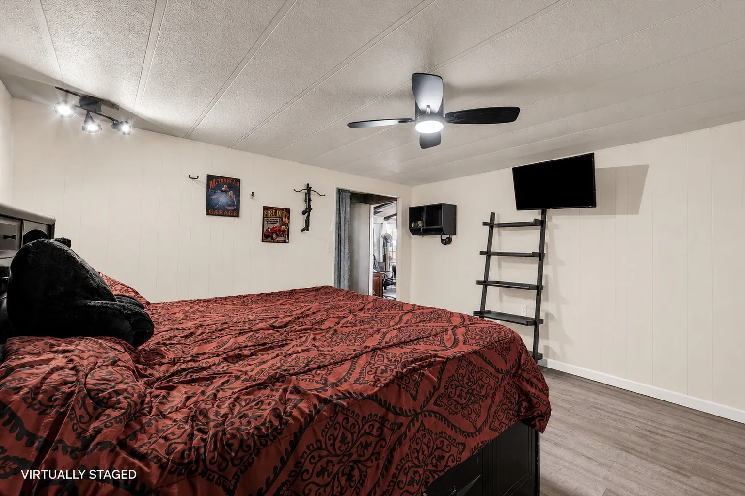 Spacious room featuring wood-finish flooring, a contemporary ceiling fan, and track lighting