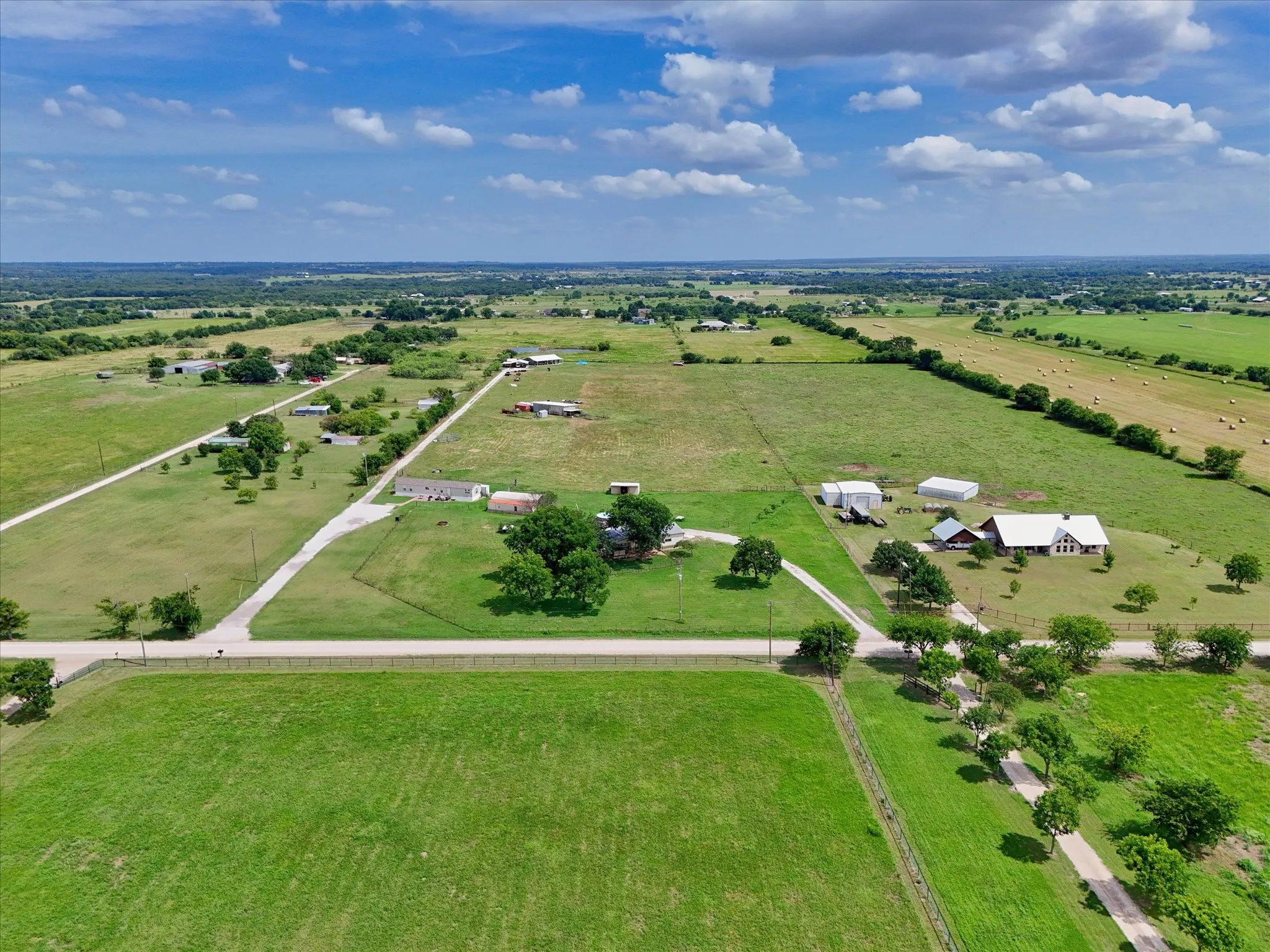 Expansive rural property featuring multiple structures, verdant green space, a long driveway, and mature trees