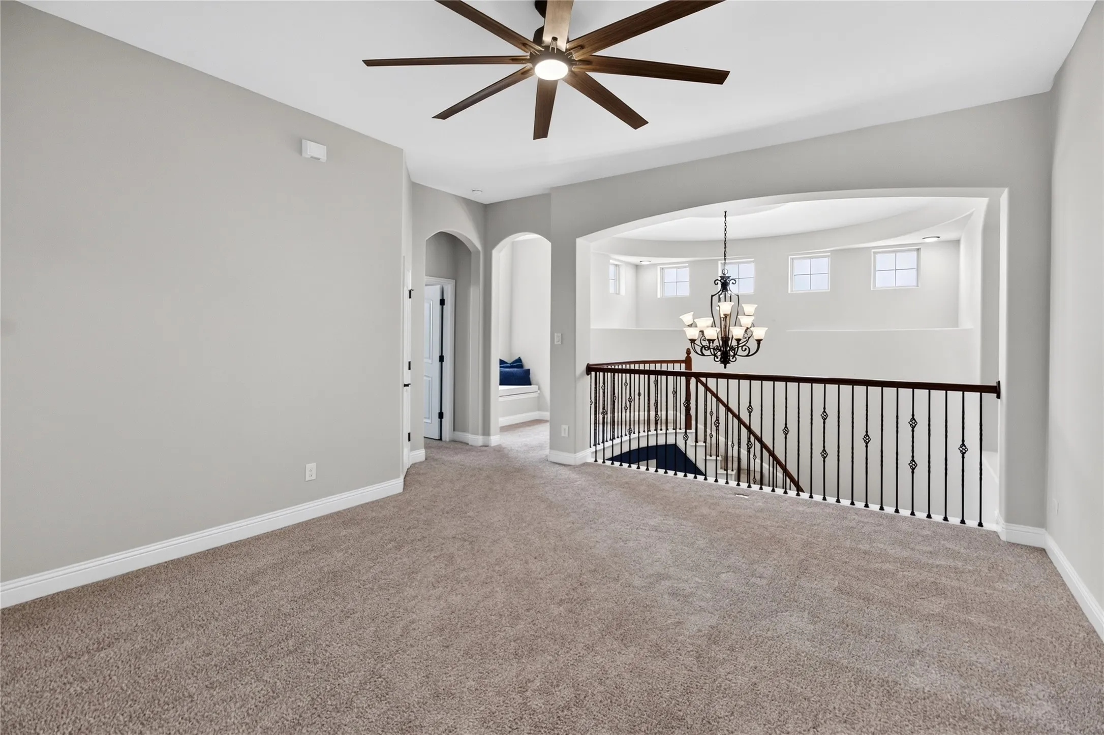 Carpeted loft area featuring a dark wood-finish ceiling fan and white baseboards
