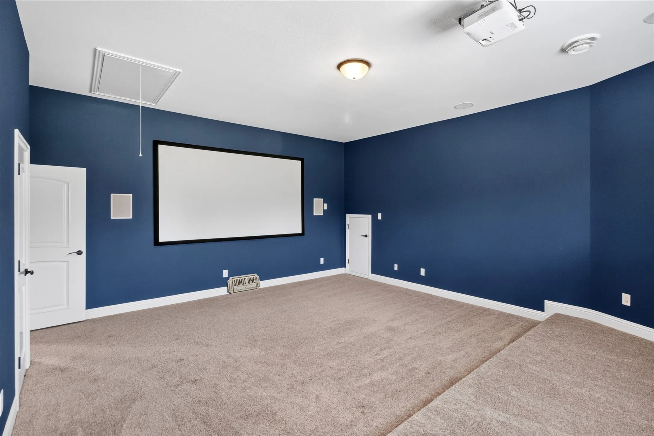 Dedicated media room featuring a large projection screen, projector, and built-in wall speakers