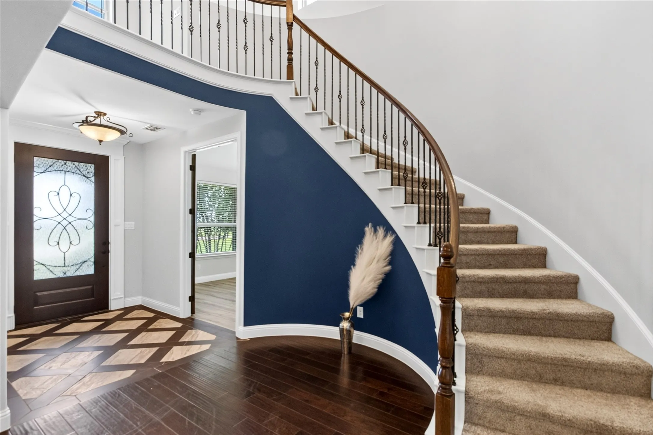 Grand entryway featuring a curved staircase with wrought iron balusters and a dark wood handrail
