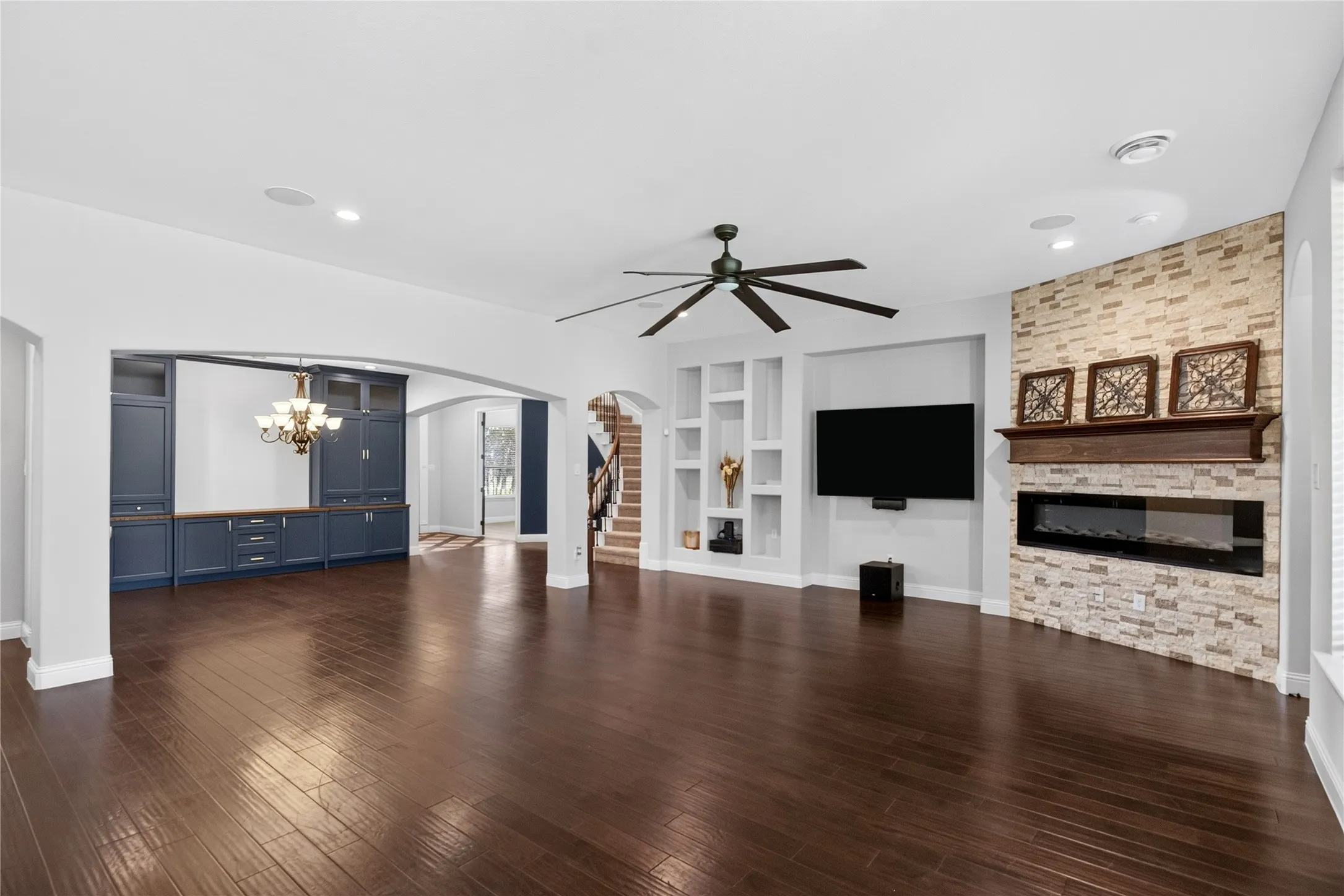 Spacious living area featuring dark wood-finish flooring, a contemporary ceiling fan, and recessed lighting