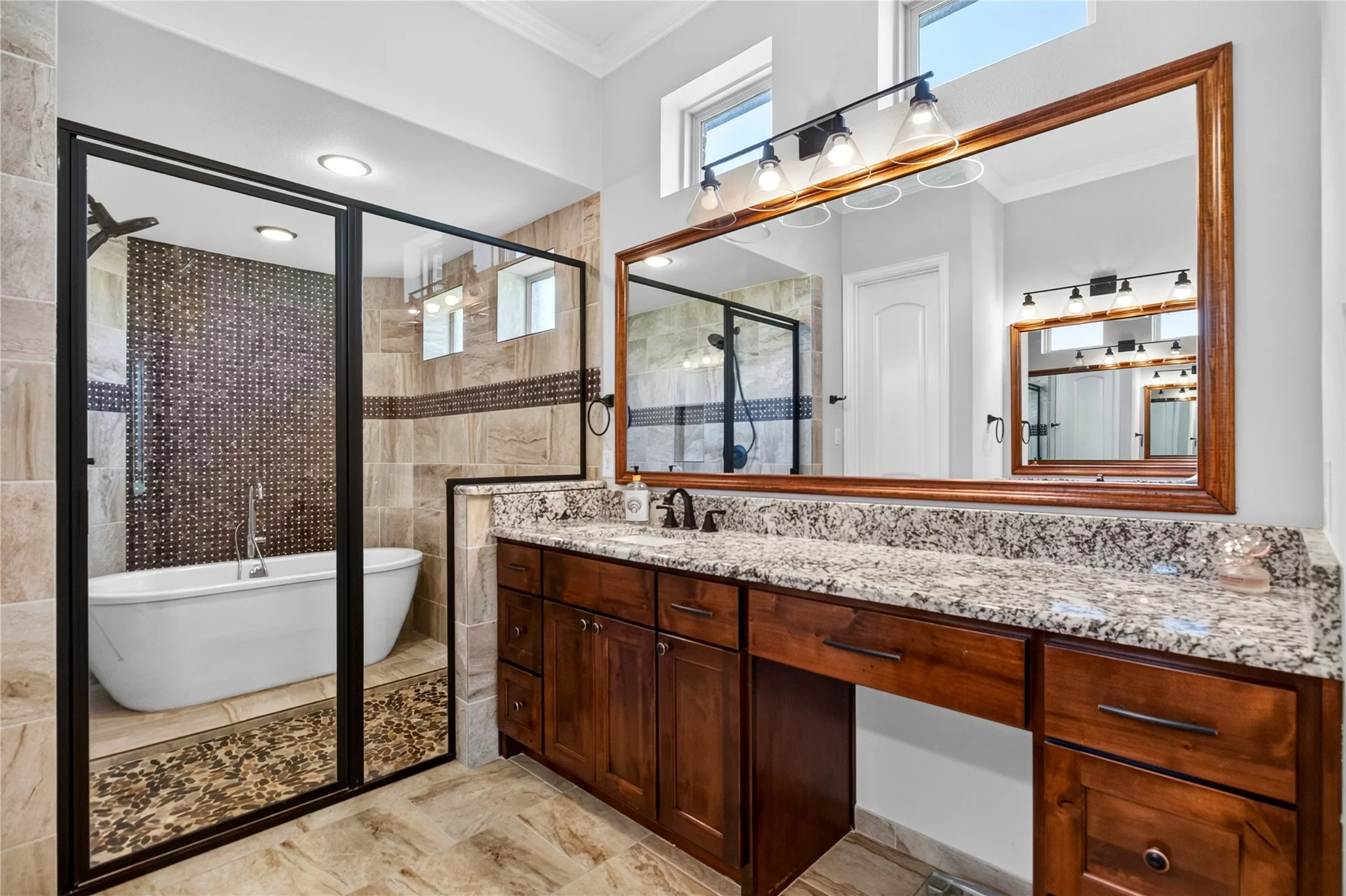 Custom-tiled shower enclosure with a freestanding soaking tub and pebble floor accent