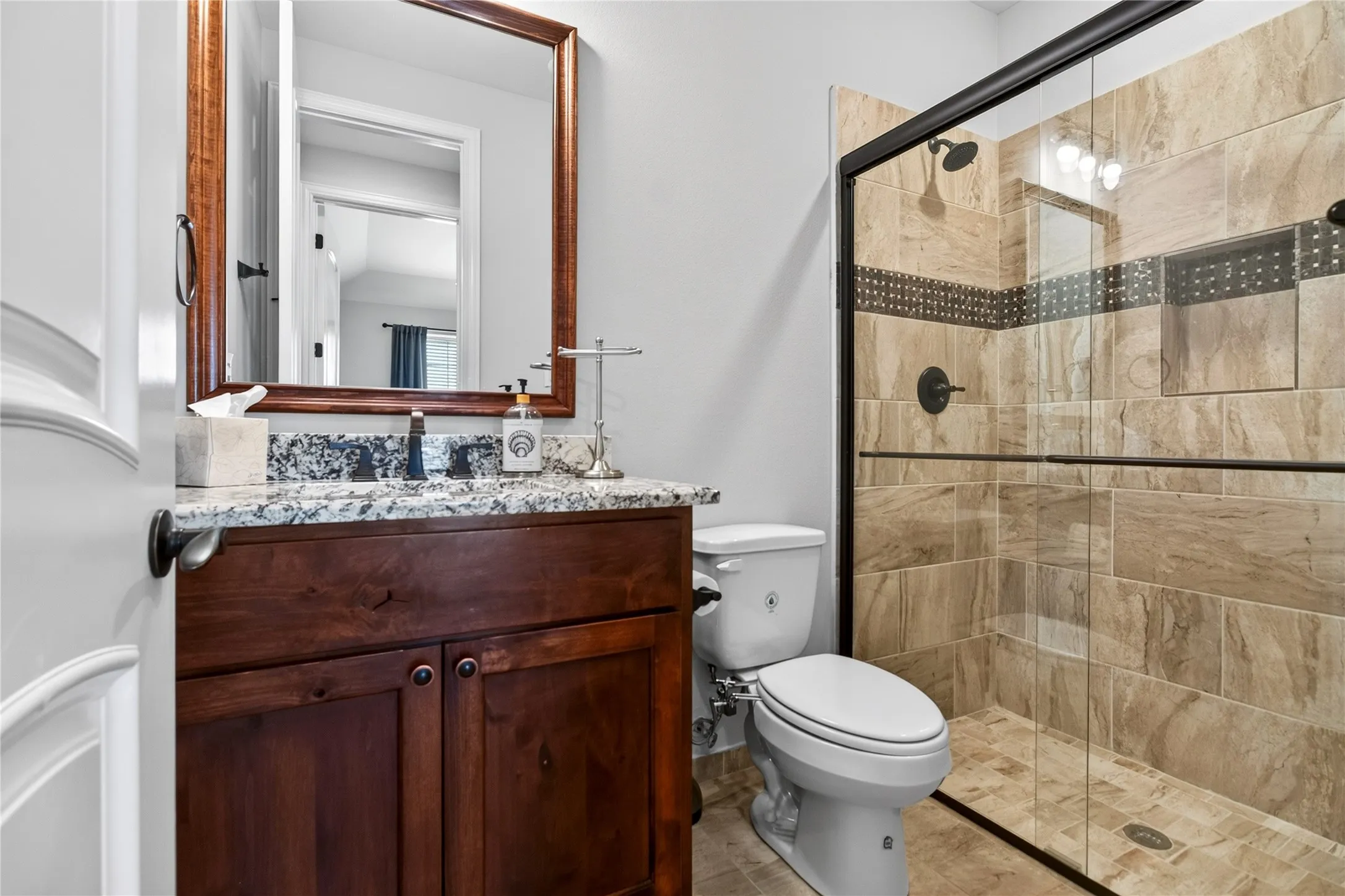 Bathroom featuring a walk-in shower with glass enclosure, decorative tile accent, and built-in niche