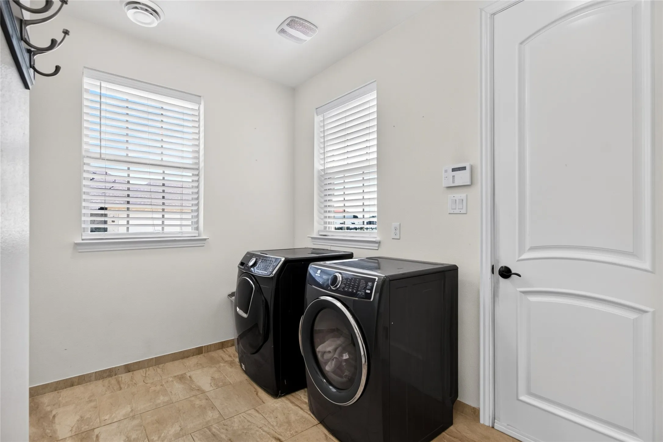 Dedicated laundry area featuring dual windows with blinds, recessed lighting, and tile flooring