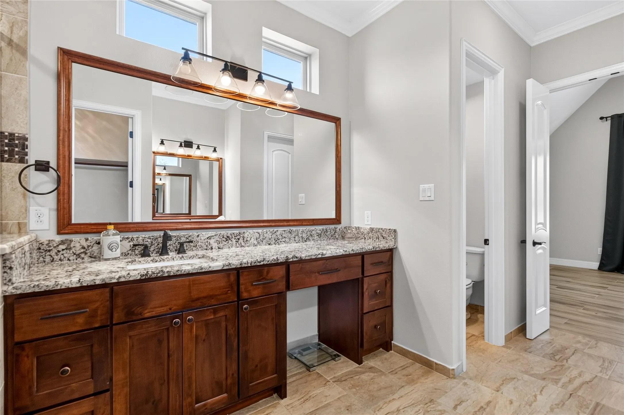 Bathroom vanity featuring dark wood cabinetry, a light granite countertop, and a large framed mirror