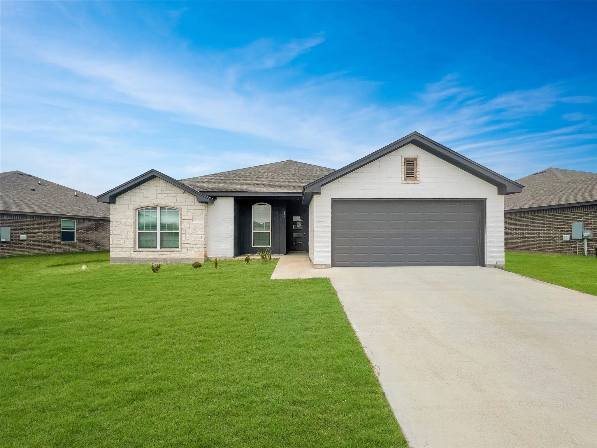 Contemporary single-story residence featuring a combination of white brick and stone accents