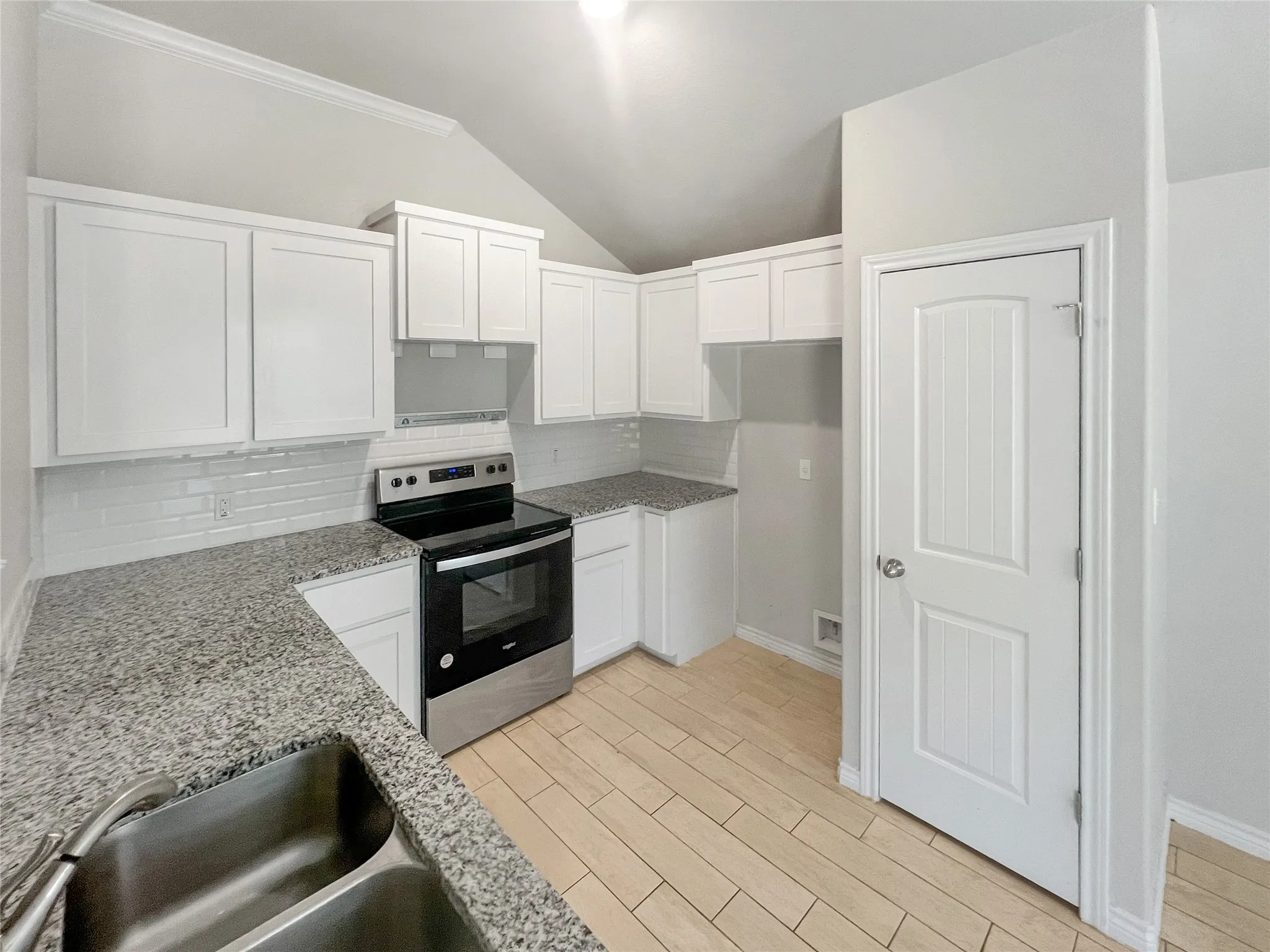 Kitchen featuring white cabinetry, granite countertops, tile backsplash, stainless steel range, and wood-finish flooring