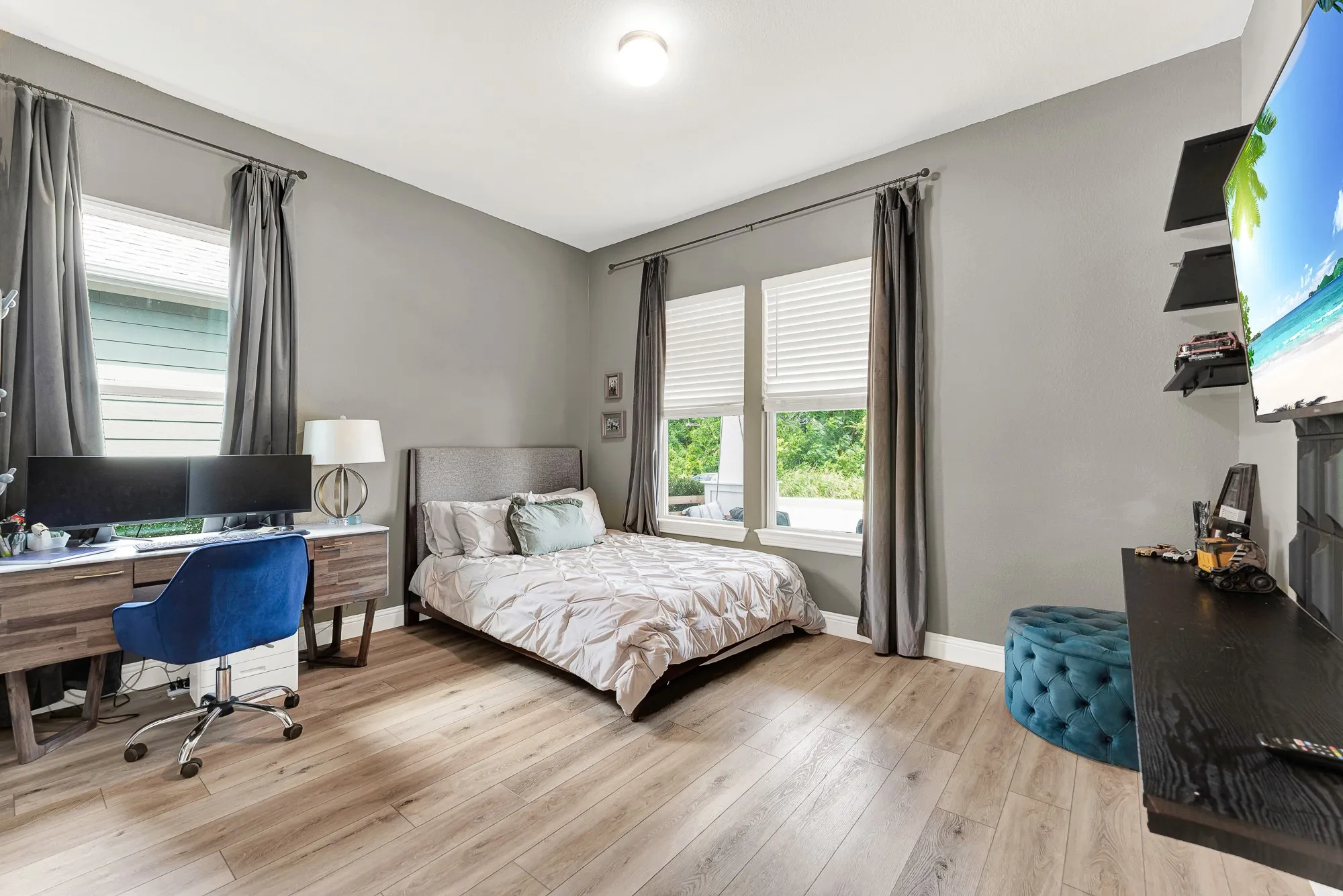 Light-filled bedroom with LVP flooring, greenspace views