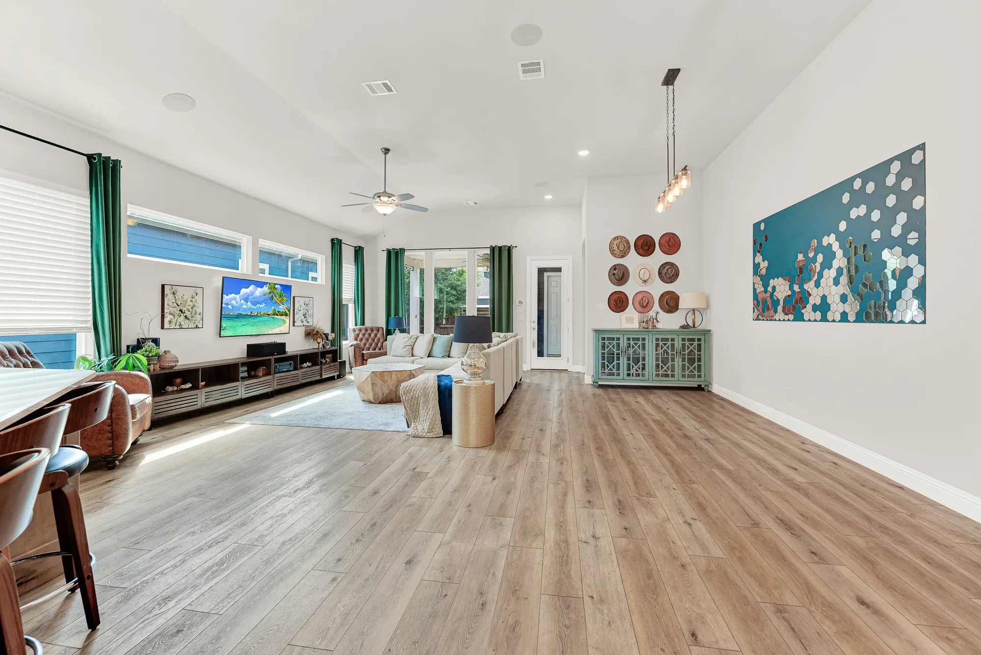Open-concept living area featuring wood-finish flooring, recessed lighting, and multiple windows