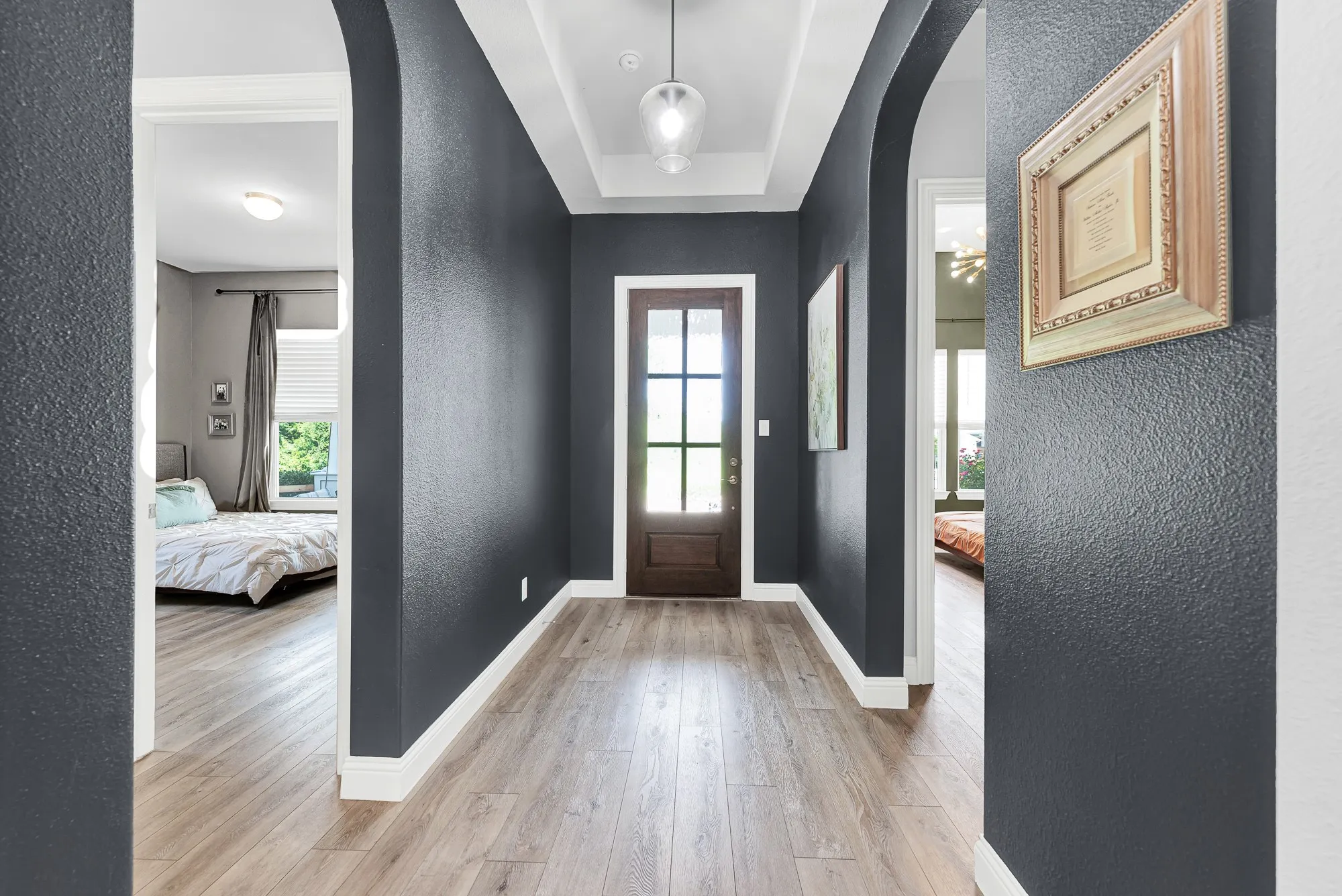 Foyer with soaring 8-ft entry door and LVP flooring, dramatic dark accent wall
