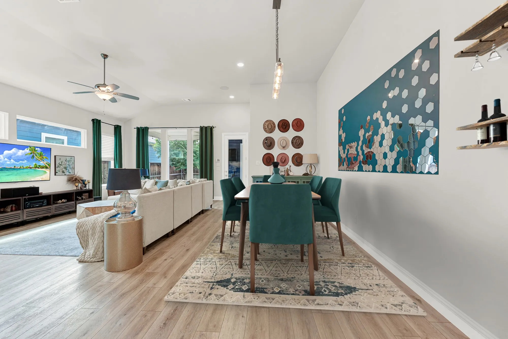 Open-concept dining area with teal accent wall and modern chandelier