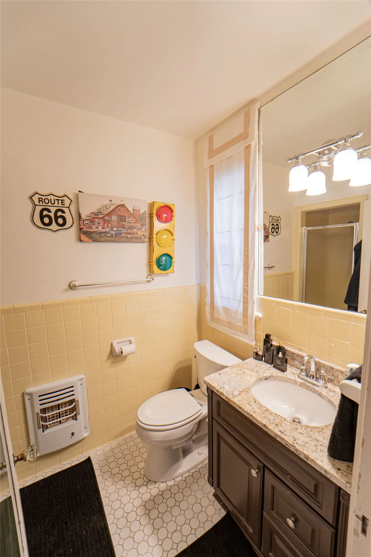 Bathroom featuring a dark wood vanity with a light-colored countertop, an undermount sink, and a large wall-mounted mirror