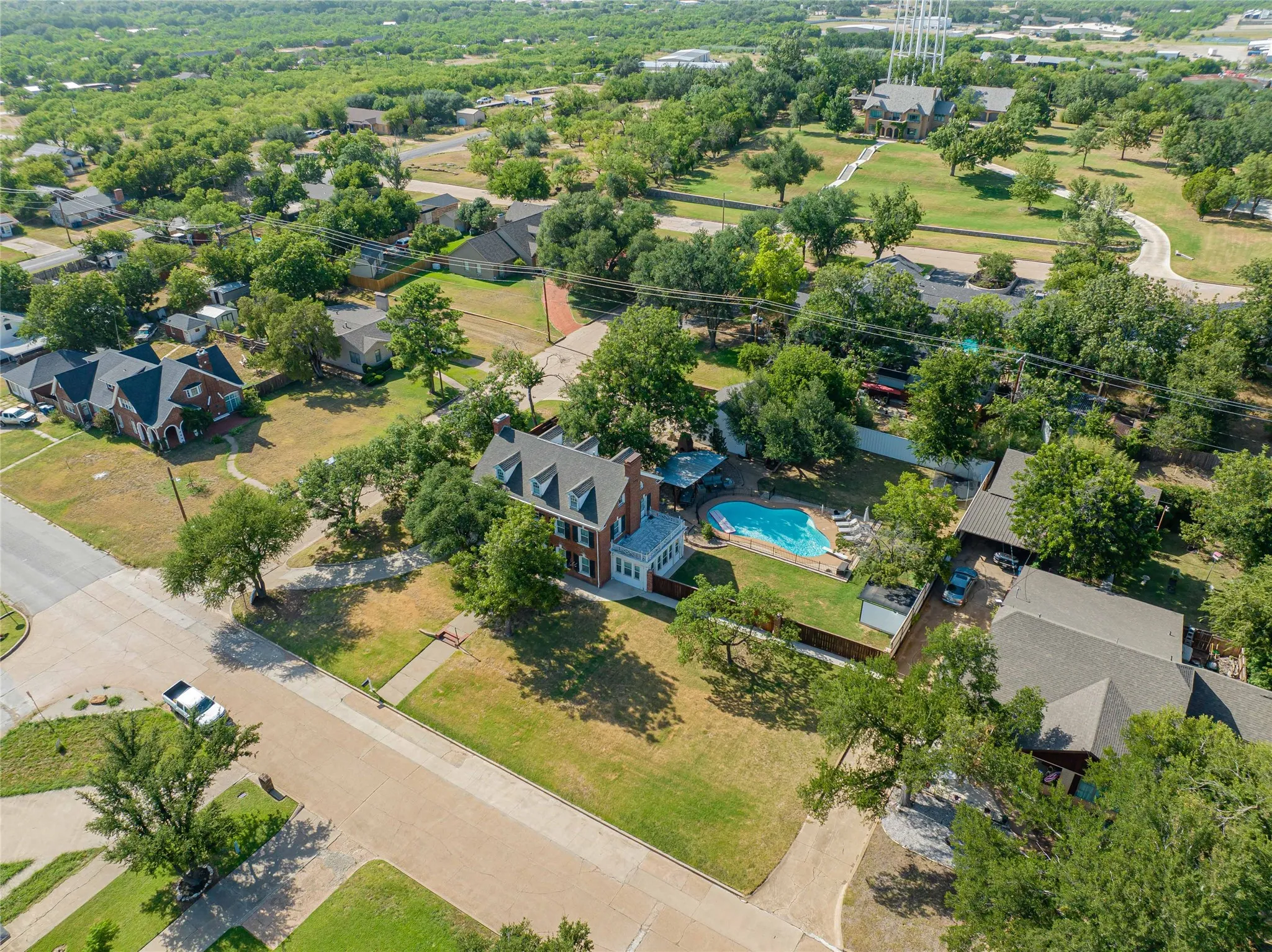 Brick residence featuring a prominent three-story facade, a dedicated swimming pool, and a private fenced yard