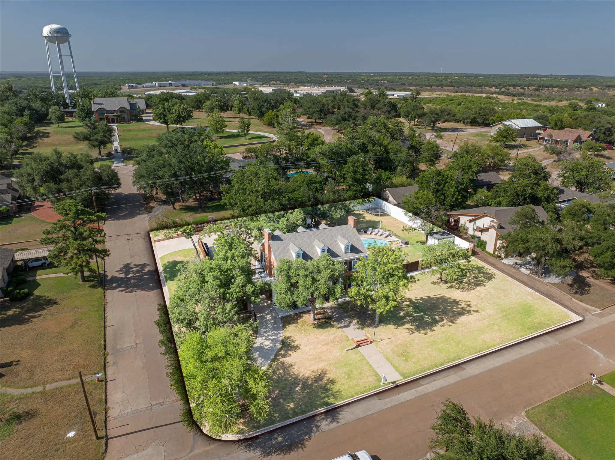 Expansive corner lot featuring mature trees and a manicured lawn