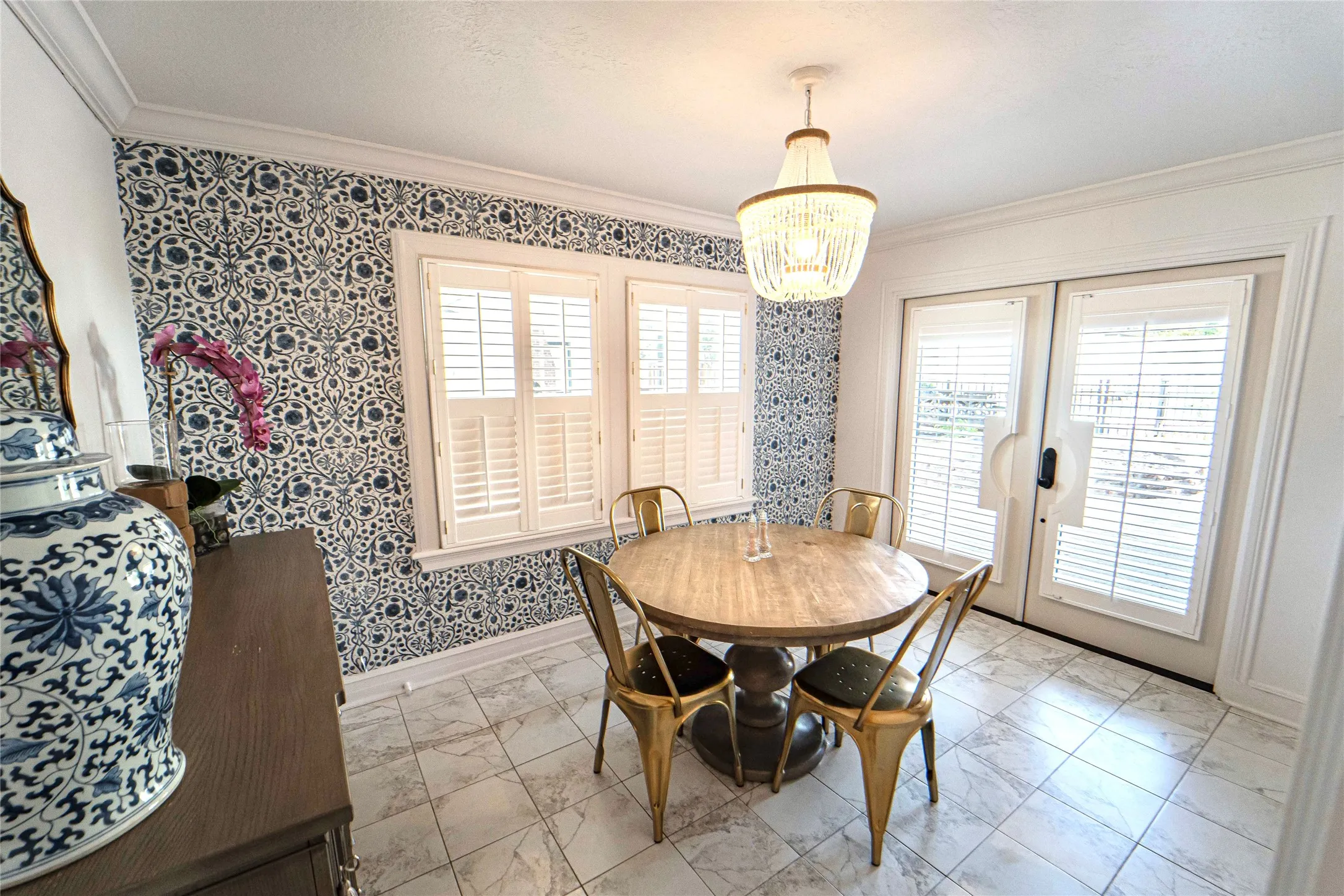 Dining area featuring a decorative ceiling fixture, patterned wall covering, and tile flooring