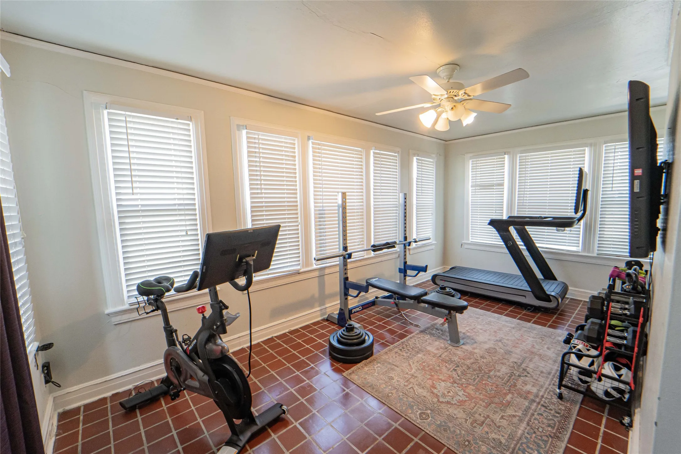 Flexible bonus room featuring a ceiling fan, multiple windows with blinds, and durable tile flooring