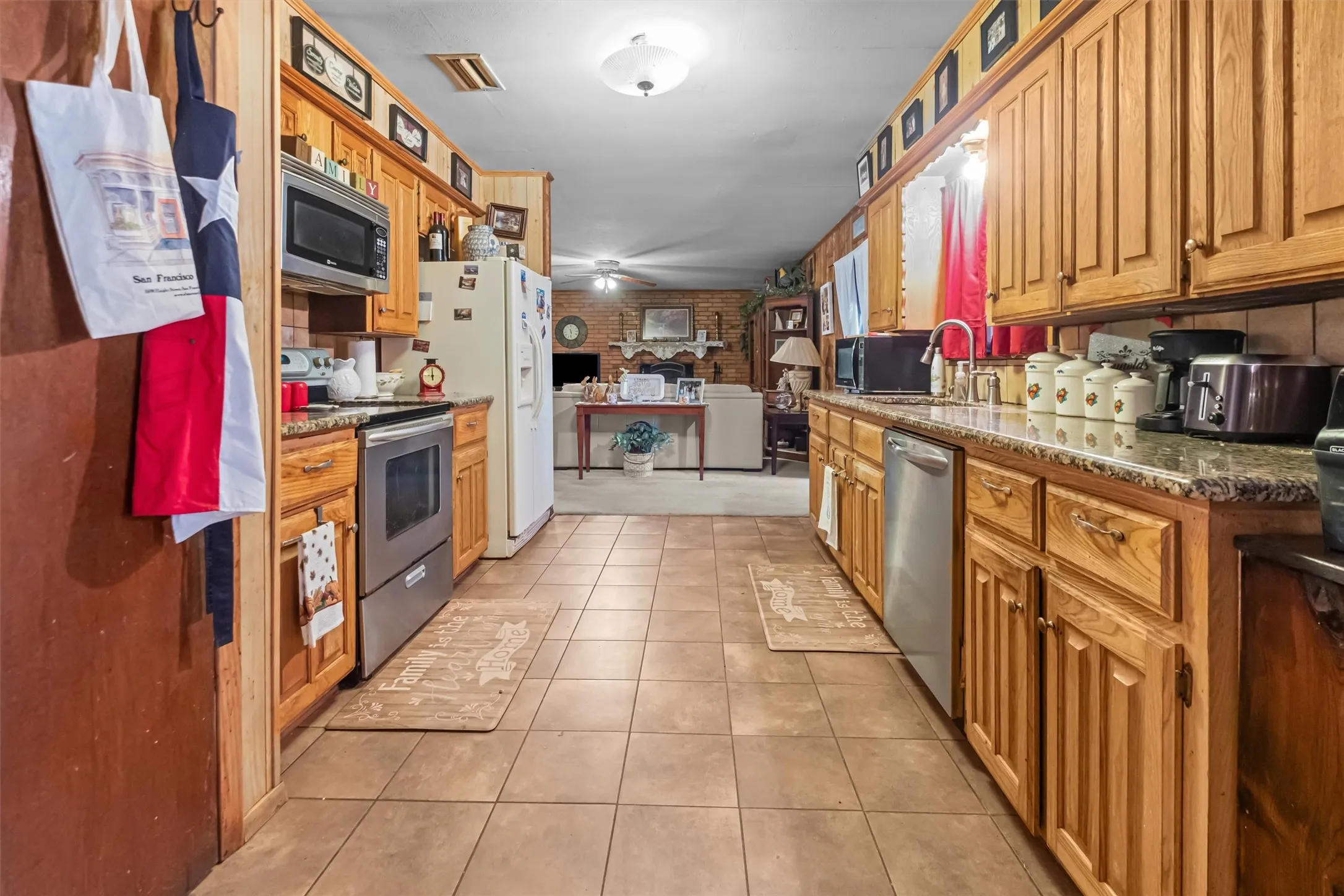 Kitchen with wood cabinetry, granite-style countertops, stainless steel appliances, and tile flooring