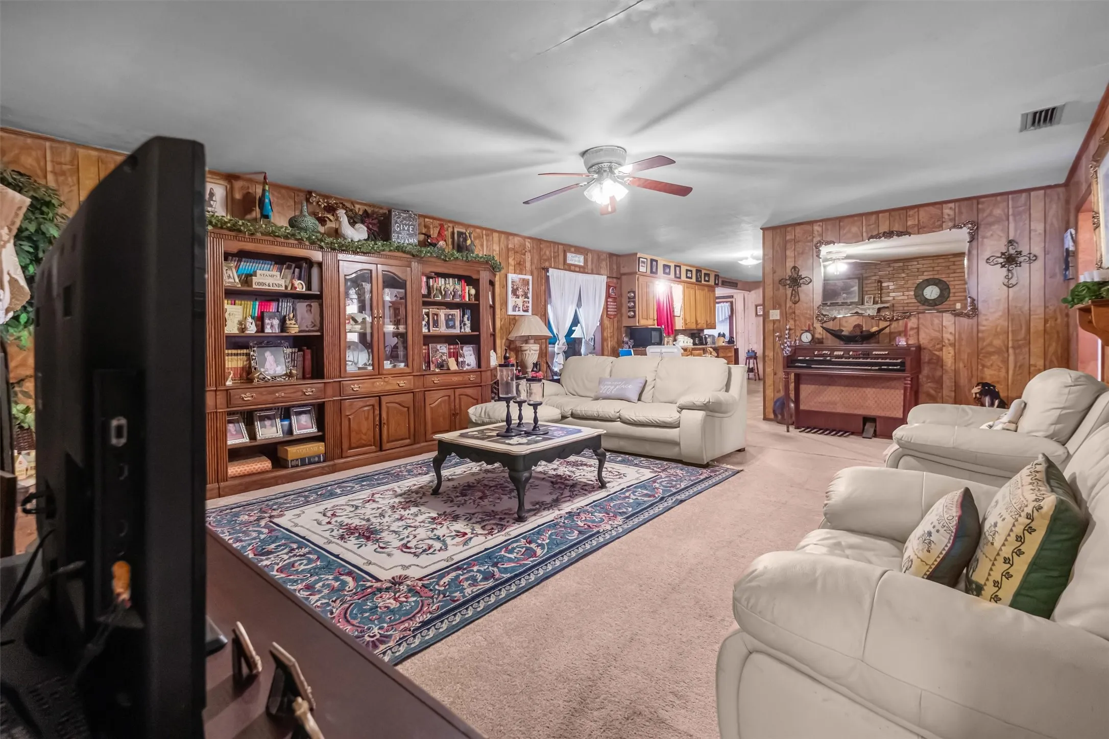 Living area featuring wood-paneled walls and neutral carpet flooring