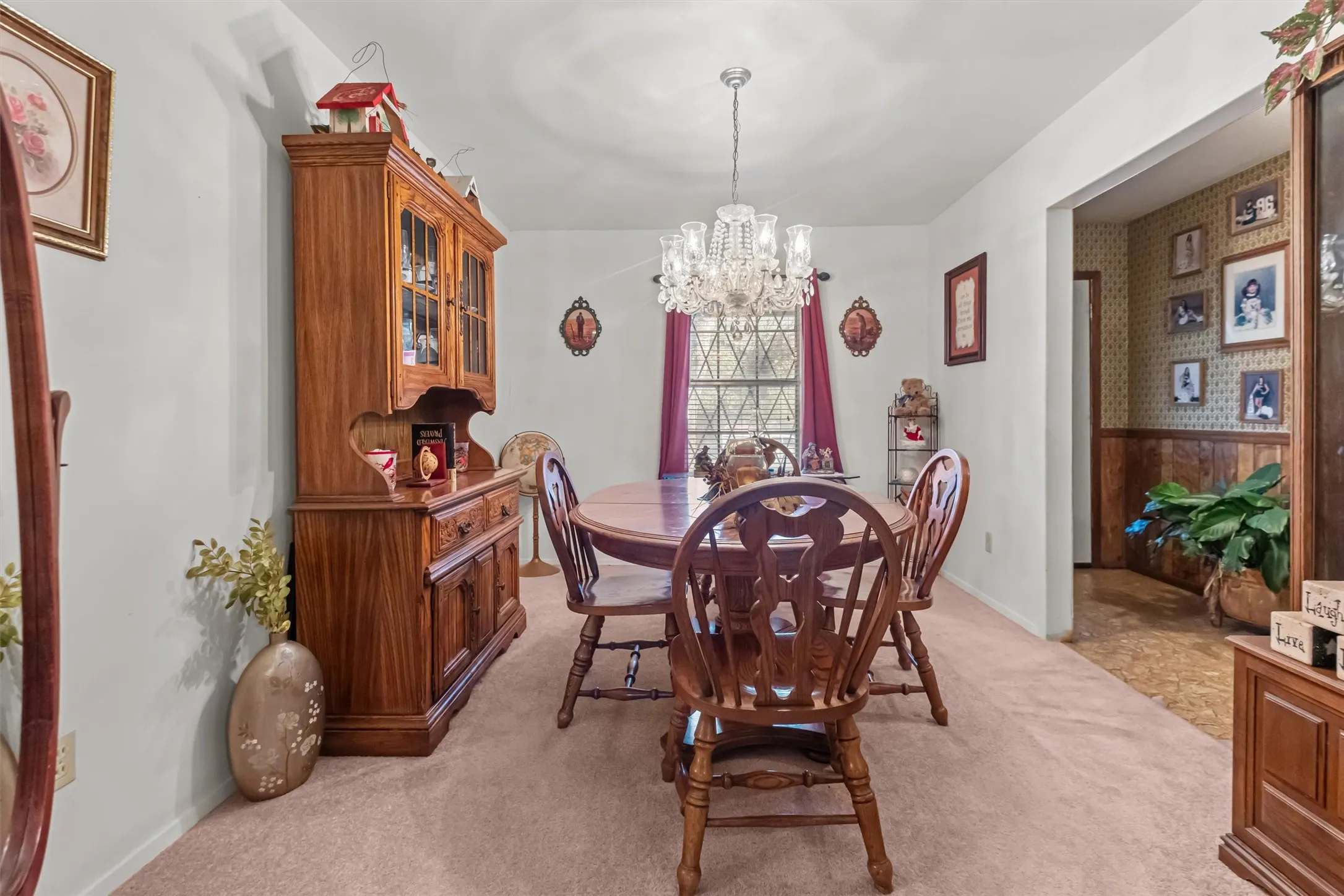 Dining space featuring a central chandelier light fixture, light-colored walls, and a window with security bars