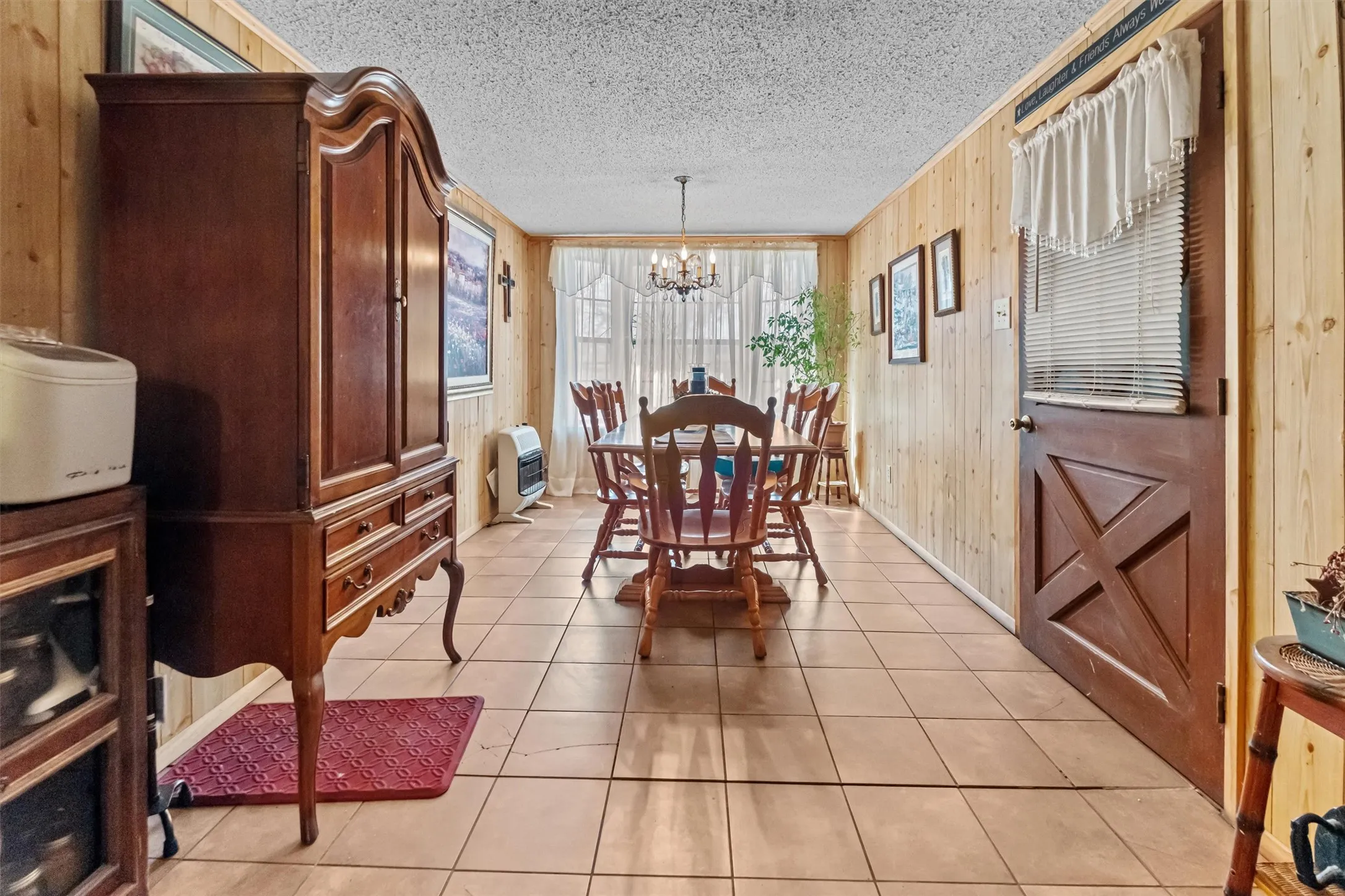 Dining space featuring wood-finish paneling, tile flooring, and a chandelier lighting fixture