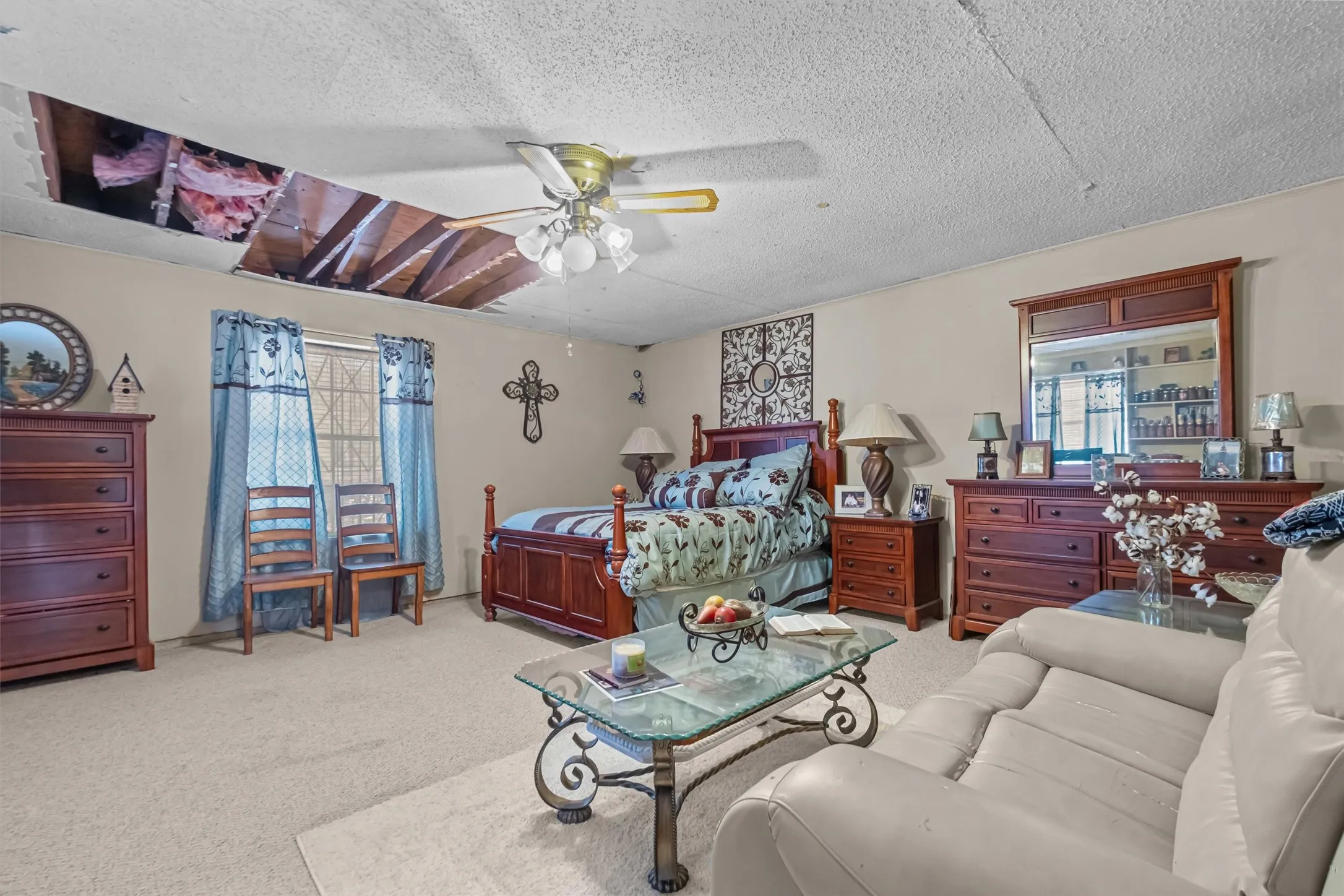 Carpeted room with a ceiling fan light fixture and a visible ceiling opening