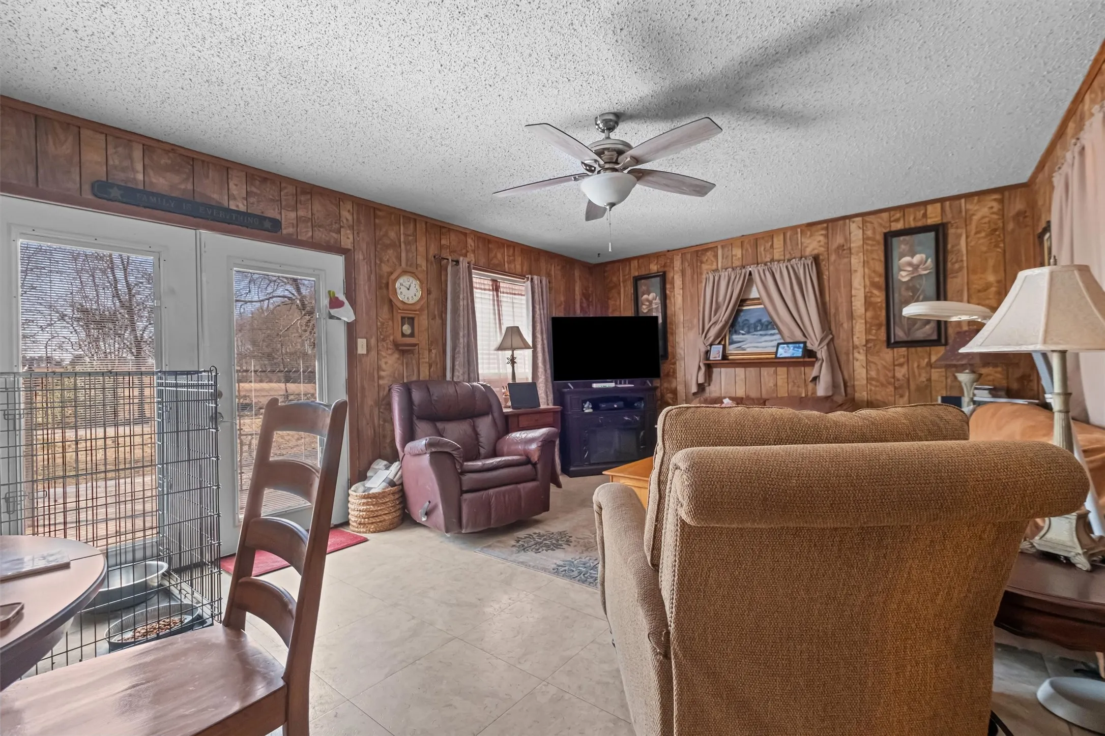 Living area featuring wood-finish paneling, a textured ceiling, and light-toned flooring