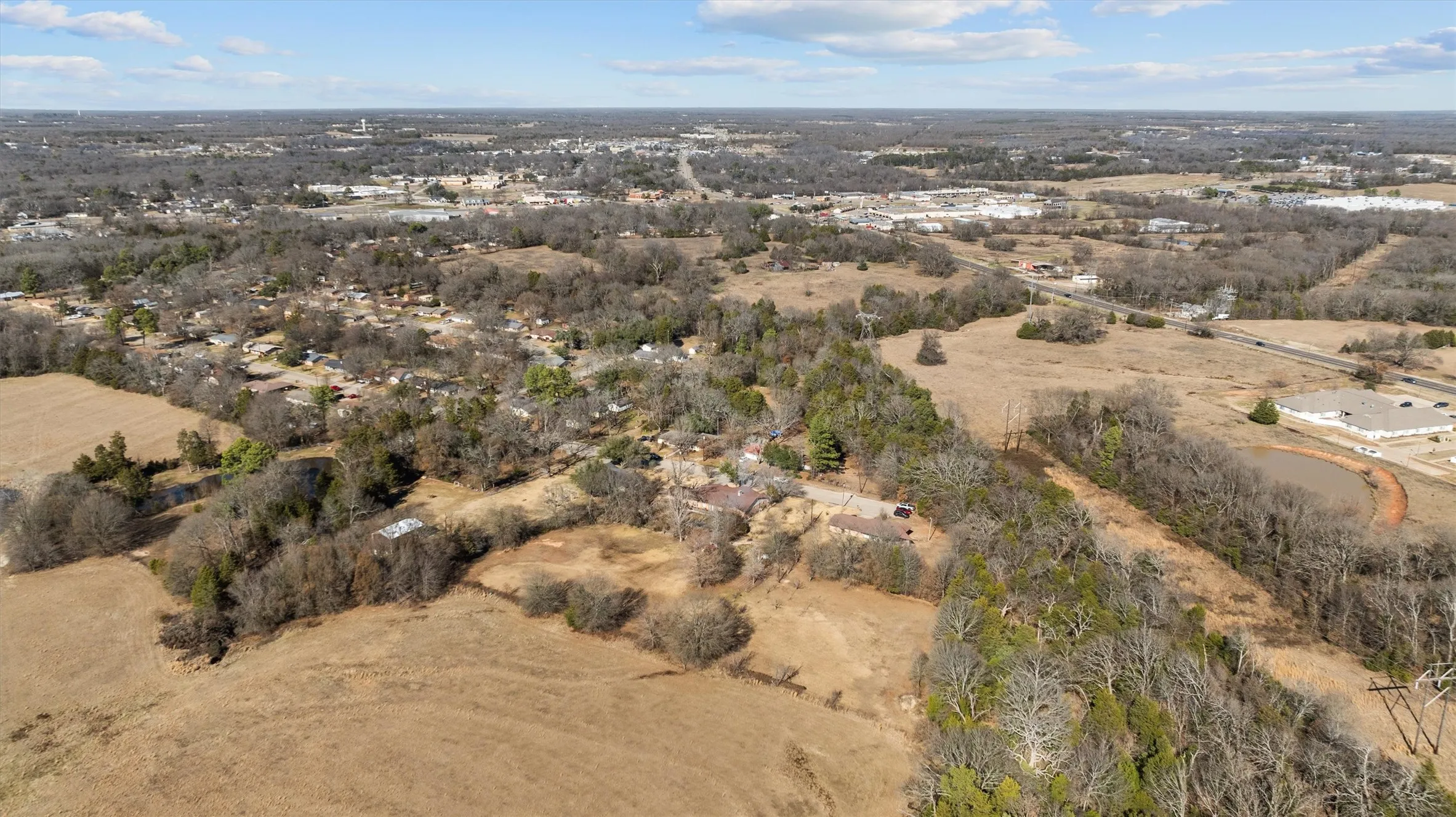 Expansive undeveloped land featuring a combination of open fields and mature tree lines