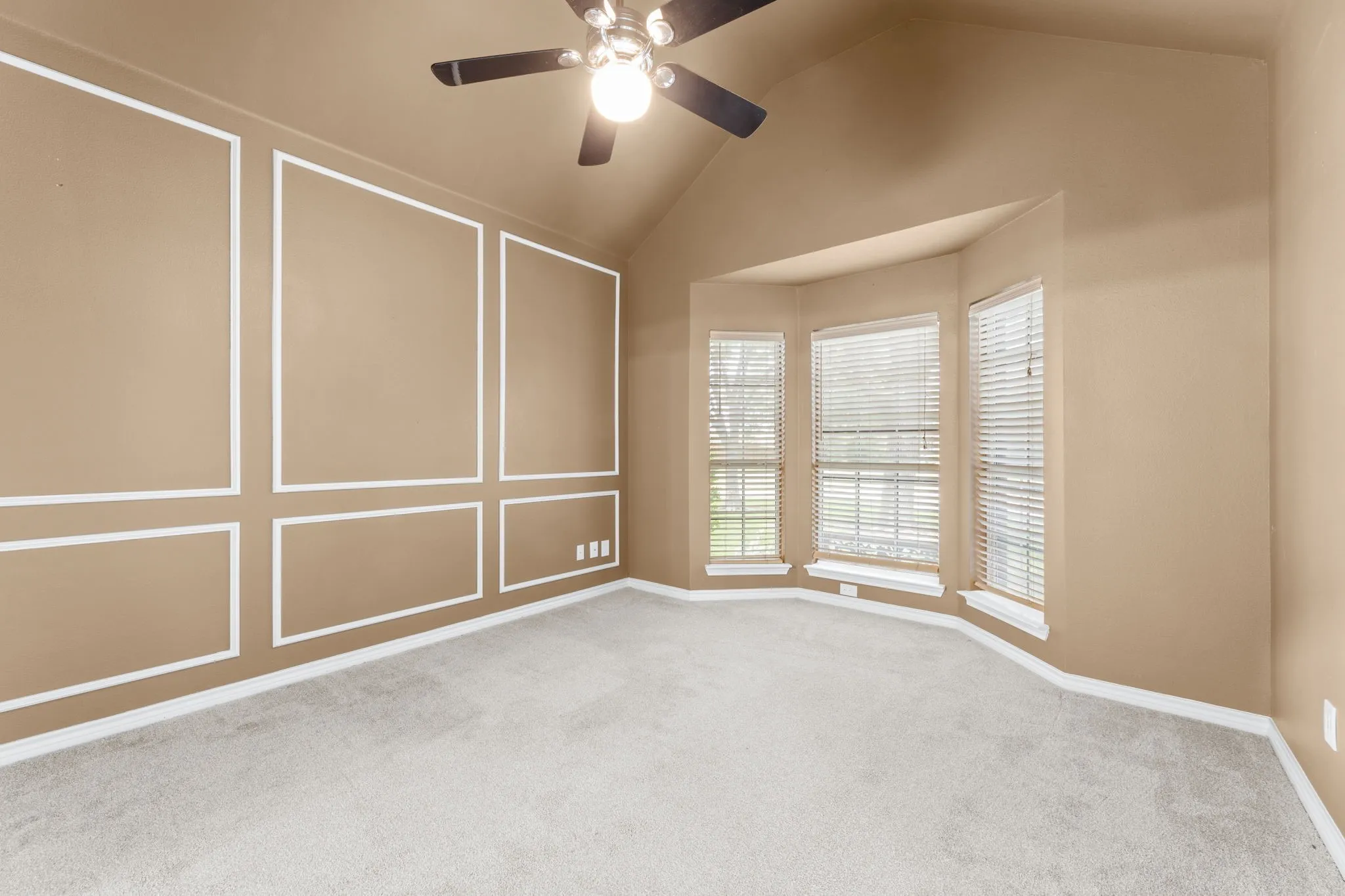 Bedroom featuring a vaulted ceiling with a ceiling fan, light gray carpet flooring, and a bay window with blinds