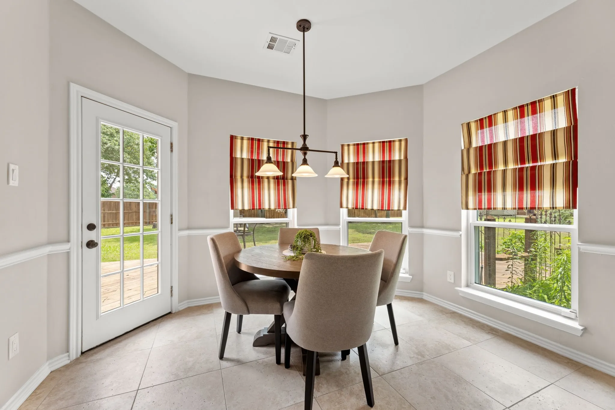 Breakfast nook featuring tile flooring, wainscoting, and a multi-light pendant fixture