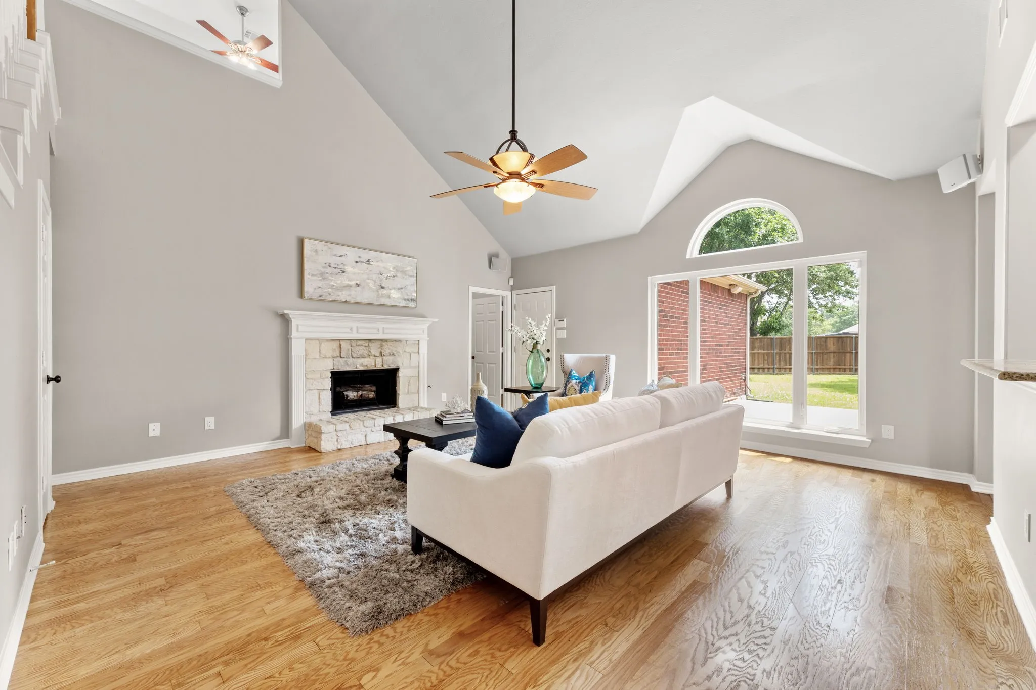 Vaulted ceilings over a stone-faced fireplace with white mantel and wood-finish flooring