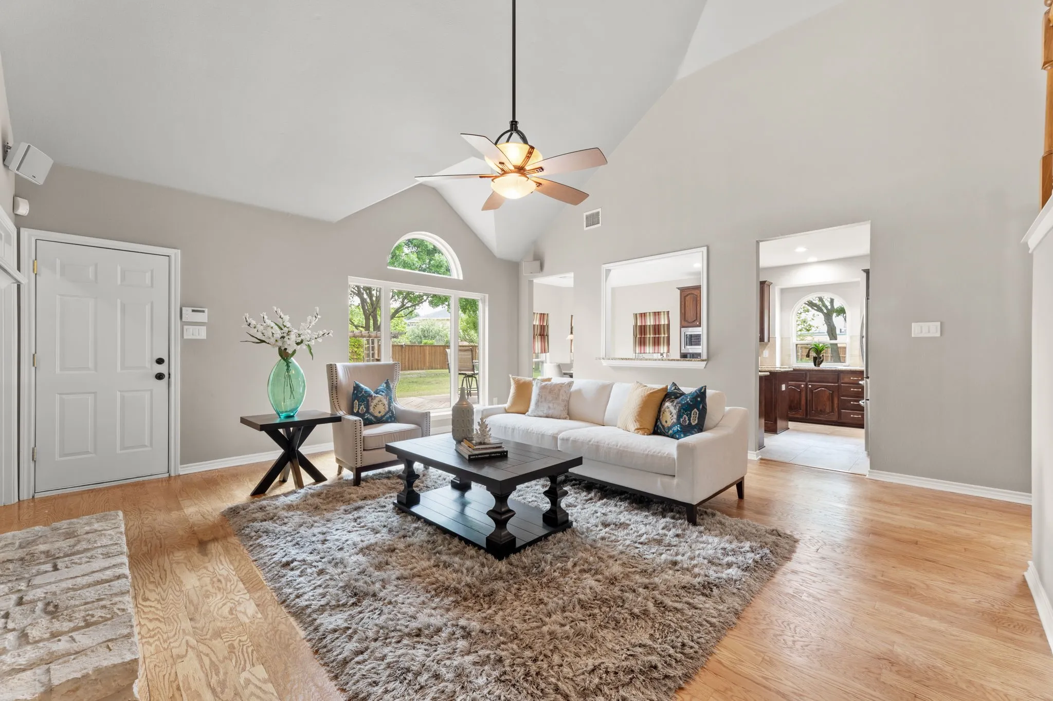 Living area with vaulted ceiling, wood-finish flooring, and a ceiling fan