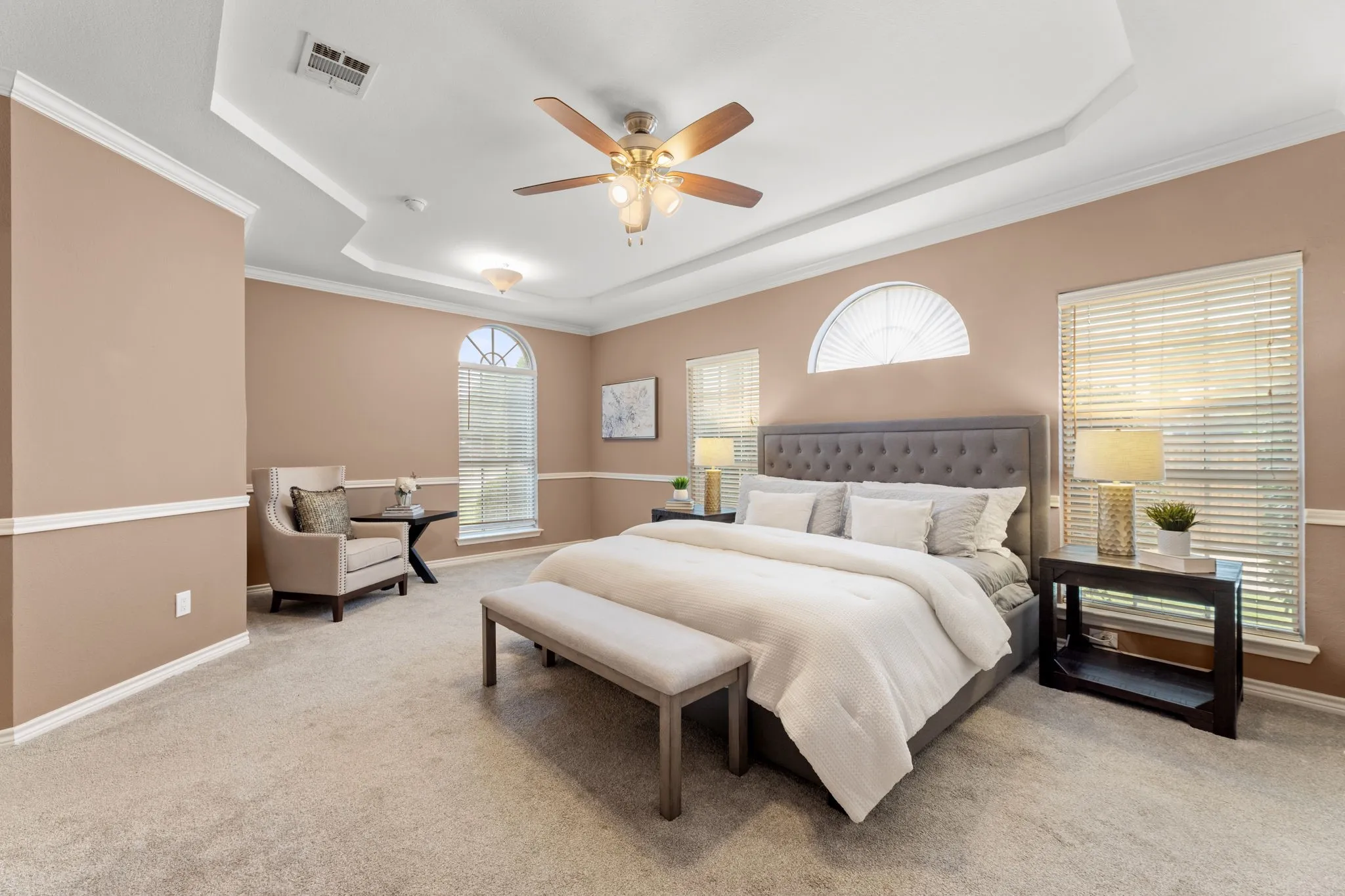 Spacious bedroom with tray ceiling, ceiling fan, and recessed lighting