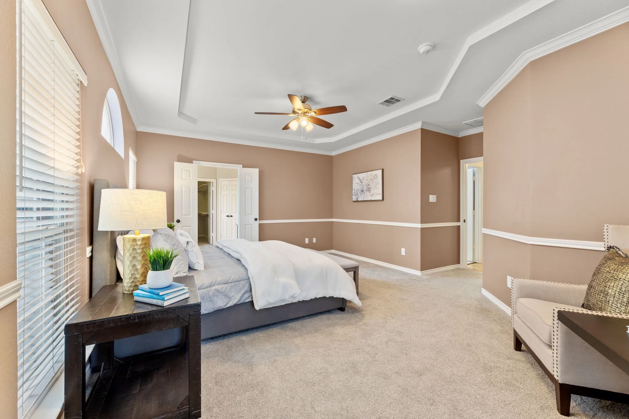 Expansive room featuring a tray ceiling with crown molding, a ceiling fan, and carpeted flooring