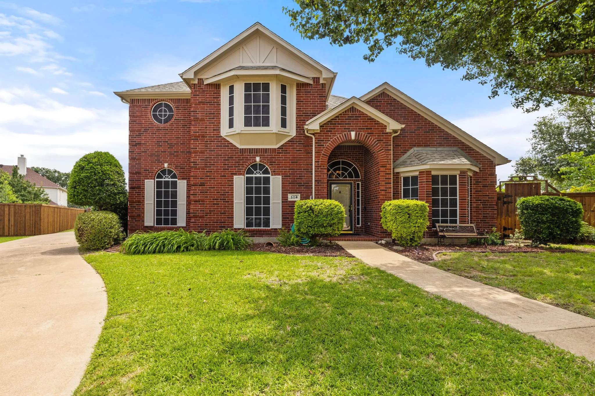 Brick exterior featuring a gabled roofline and manicured landscaping