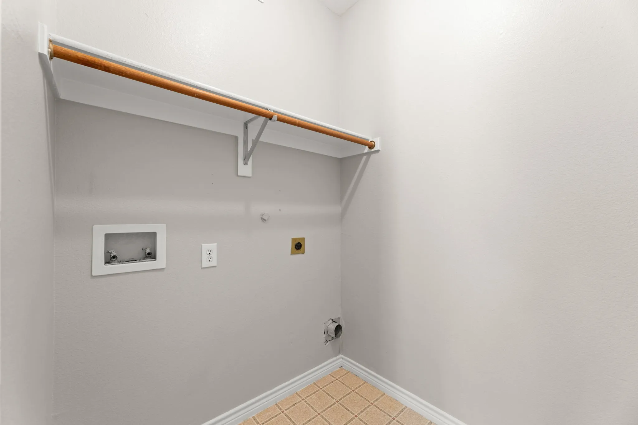 Dedicated laundry area featuring a wood-finish hanging rod, utility hookups, and tiled flooring
