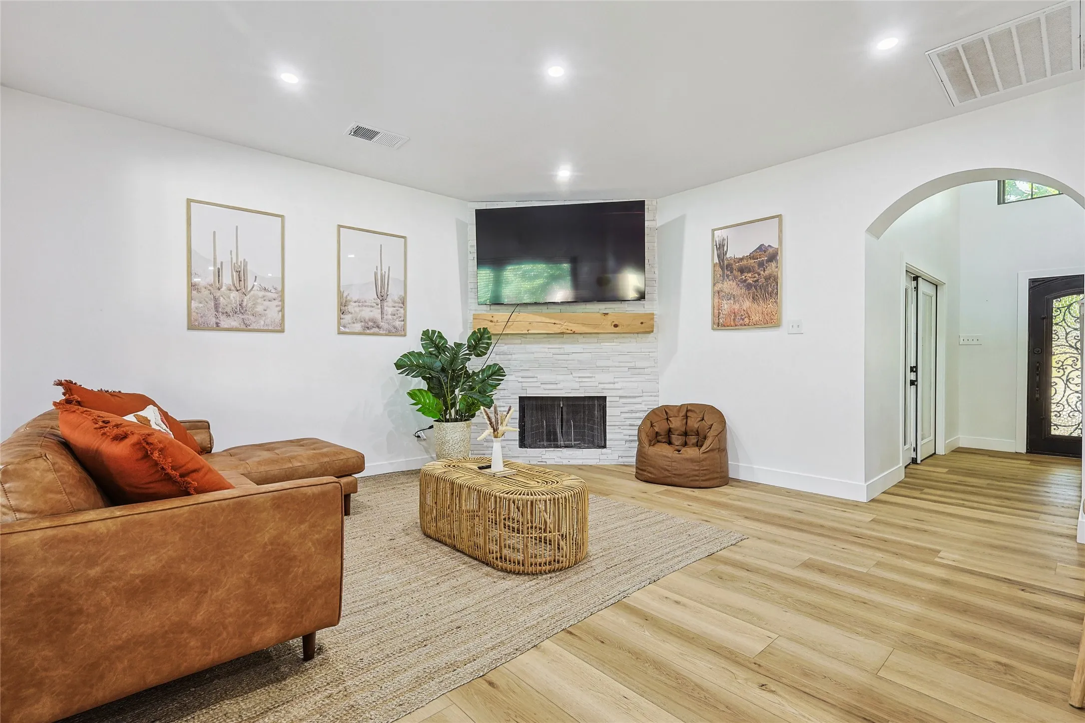 Living area with arched walkways, a large fireplace, visible vents, and wood finished floors