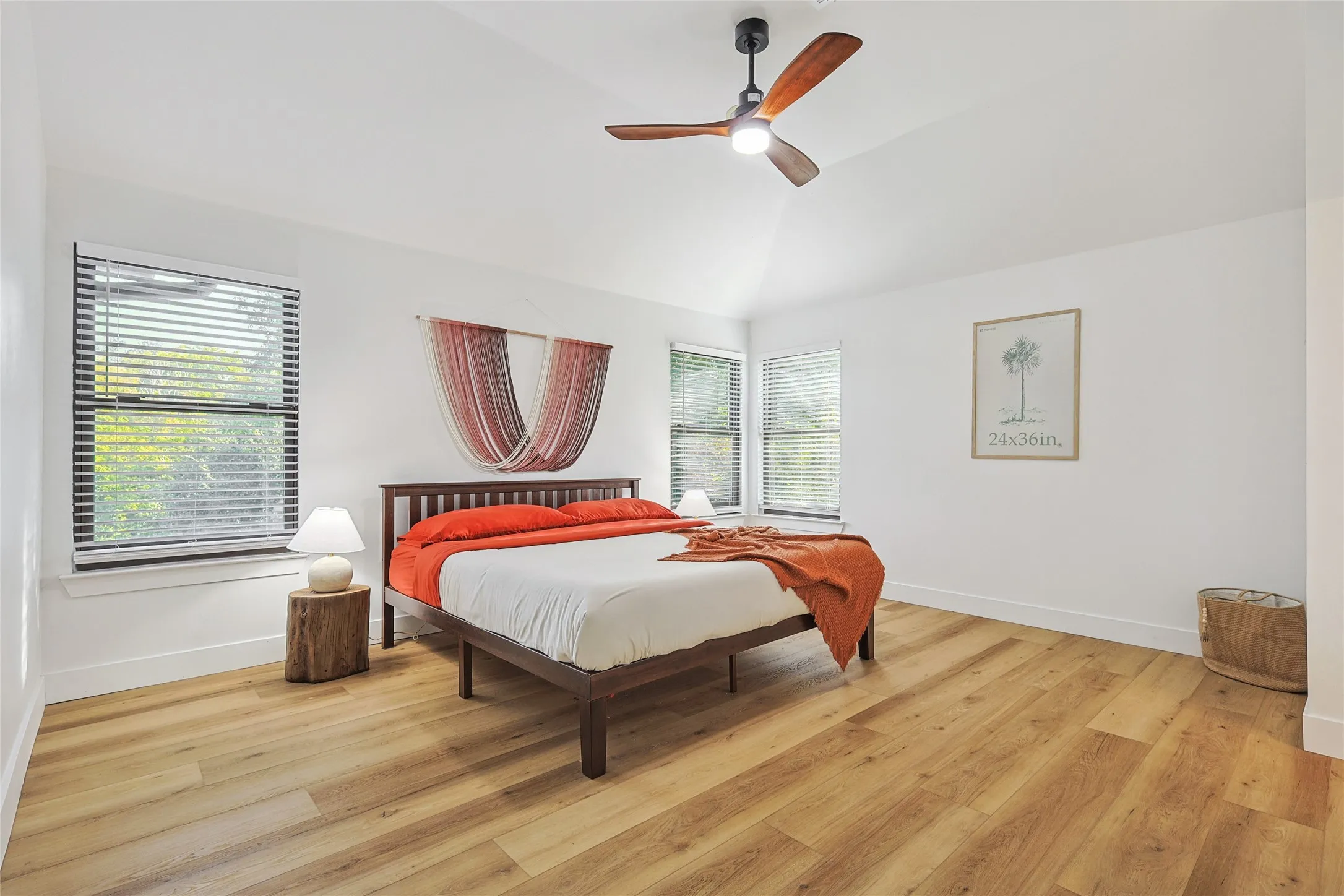 Bedroom featuring baseboards, vaulted ceiling, light wood-style floors, and a ceiling fan