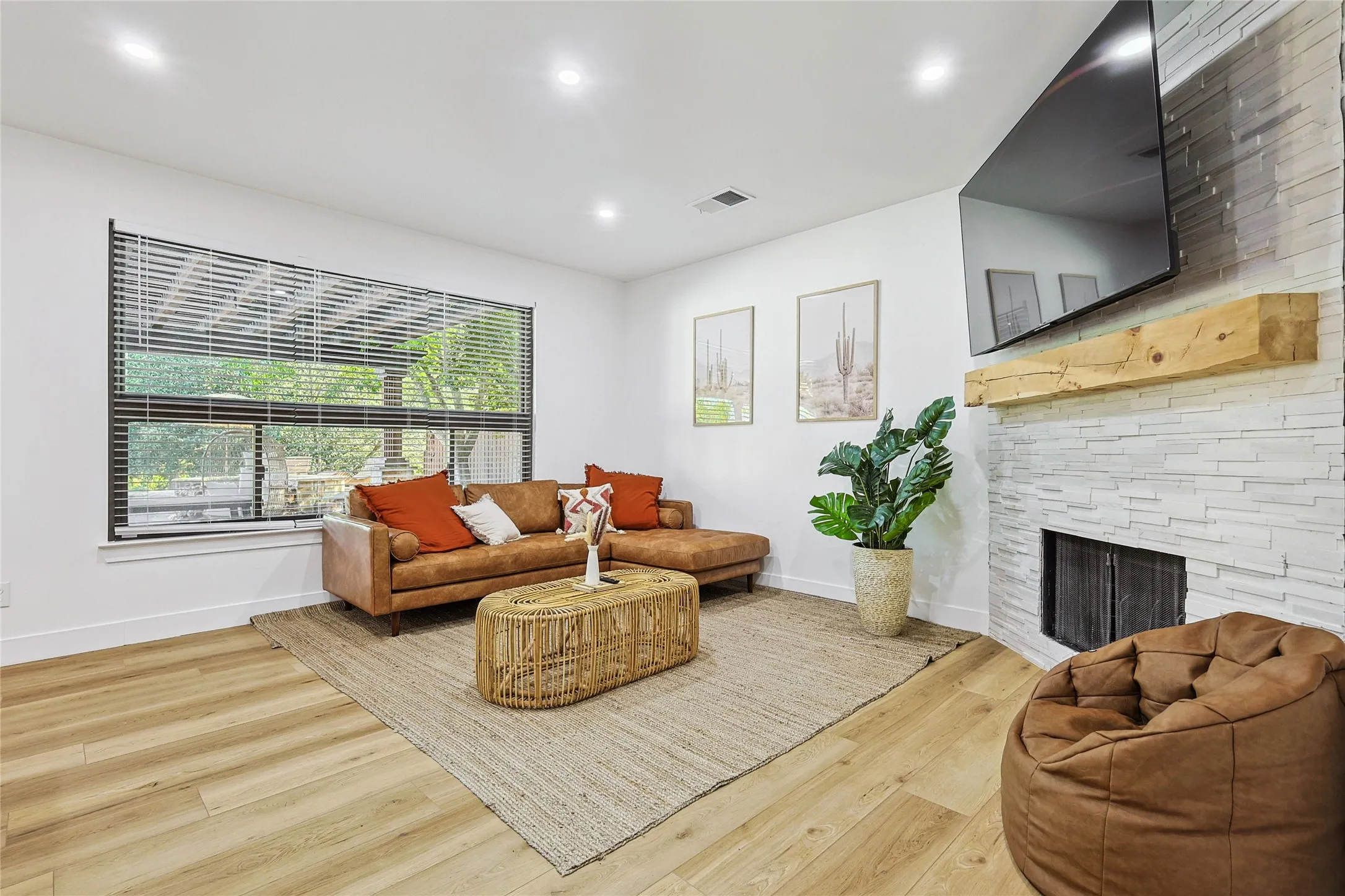 Living room featuring visible vents, baseboards, wood finished floors, recessed lighting, and a stone fireplace
