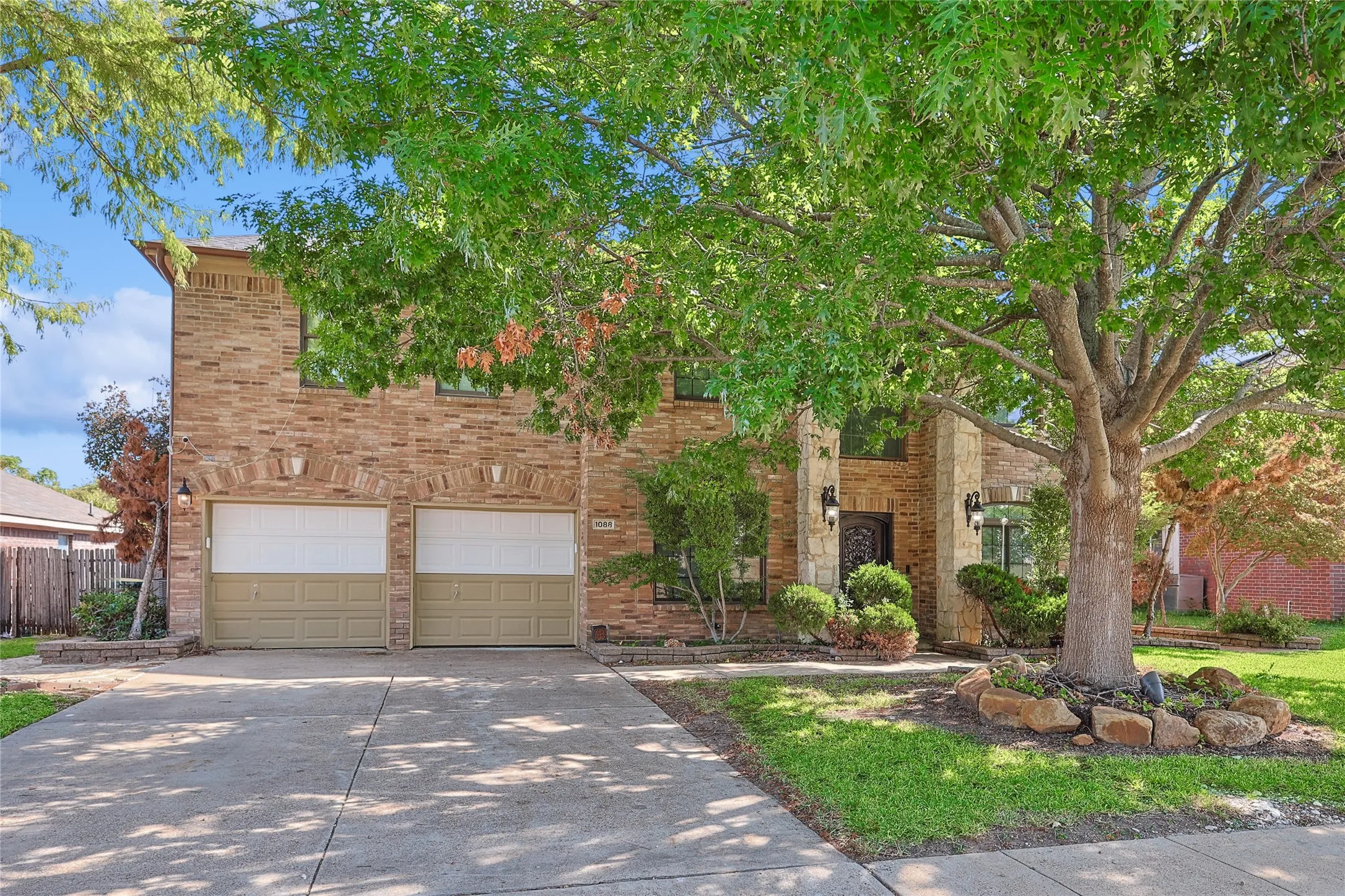 View of front facade featuring fence, a garage, brick siding, and concrete driveway