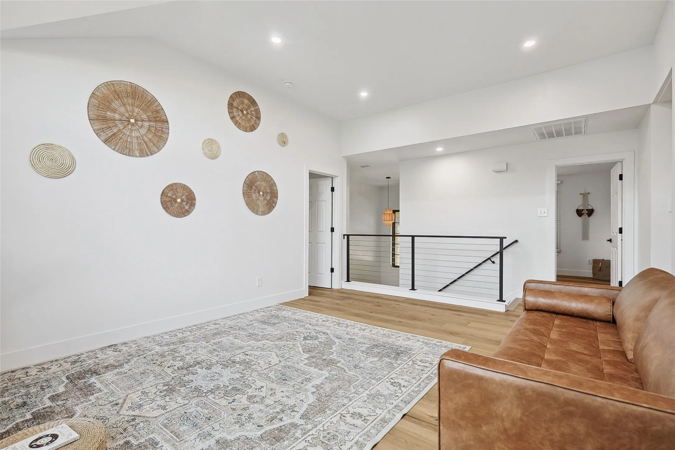 Sitting room featuring an upstairs landing, light wood-style flooring, visible vents, baseboards, and recessed lighting