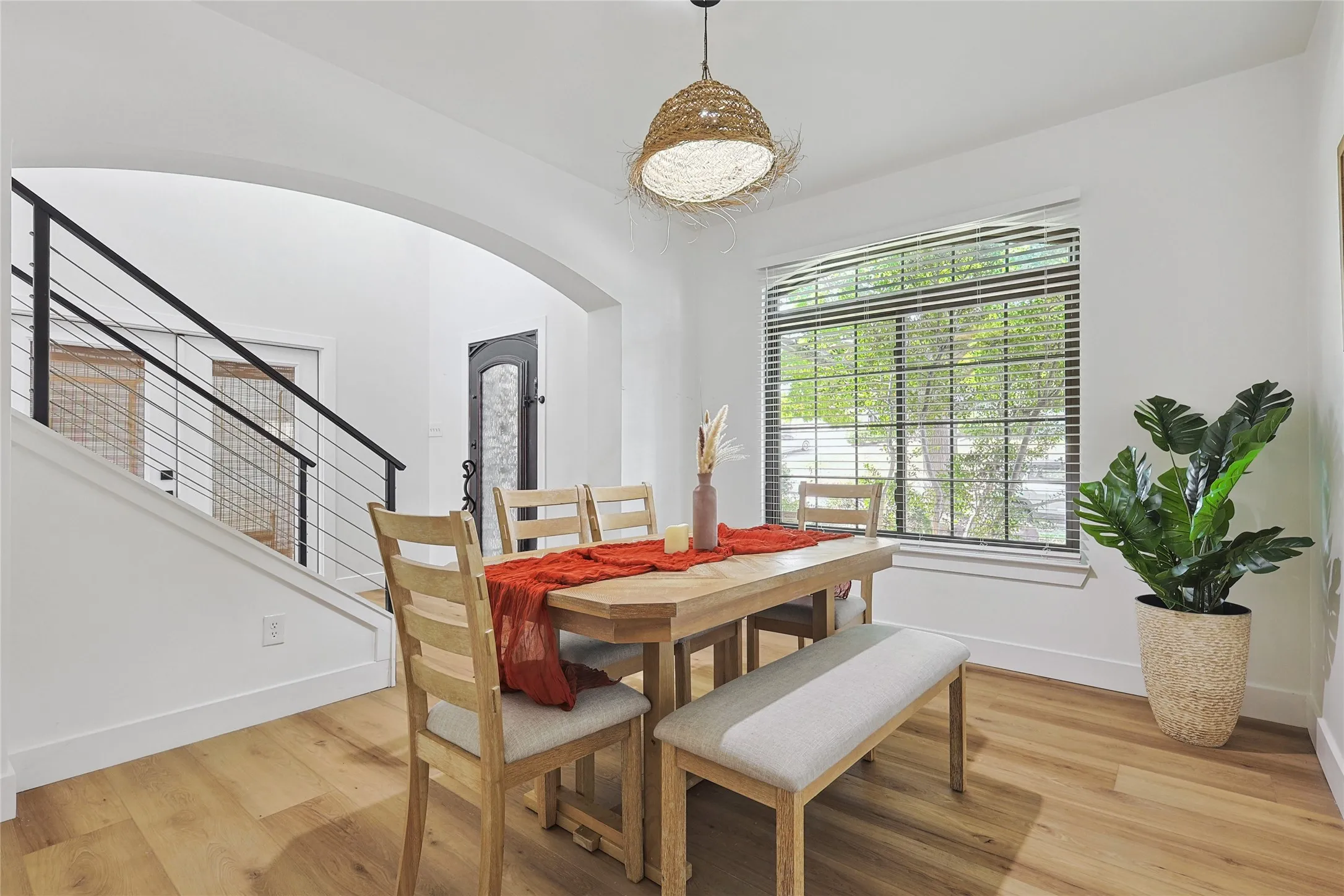 Dining area with arched walkways, baseboards, light wood finished floors, and stairs