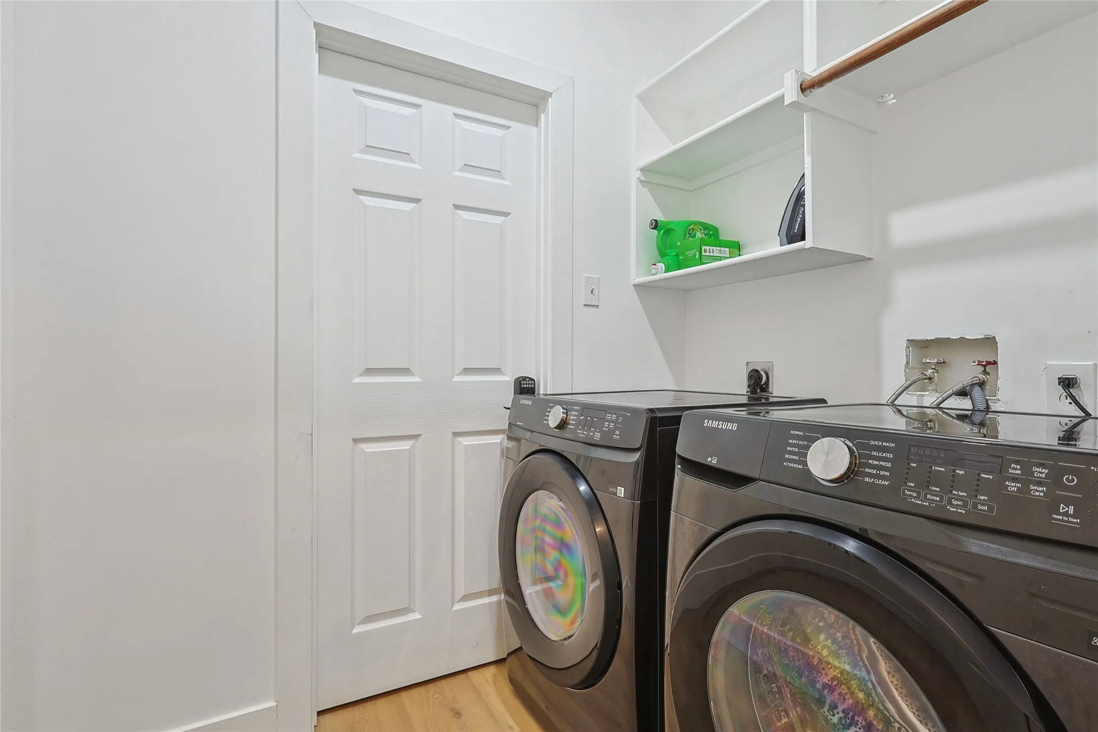 Clothes washing area featuring light wood-style flooring, washing machine and clothes dryer, and laundry area