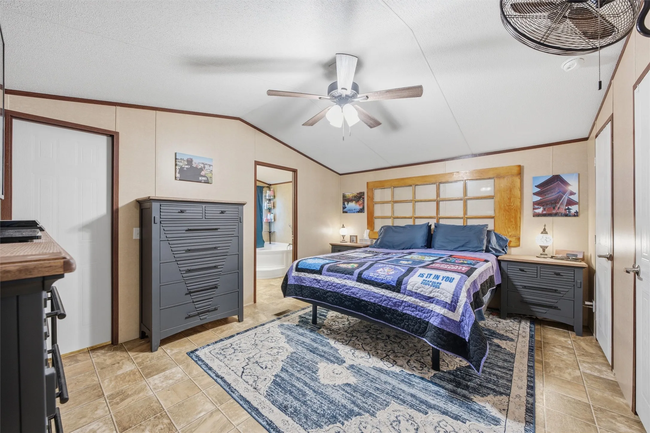 Bedroom featuring a ceiling fan with integrated lighting, wood-finish flooring, and light-toned paneled walls with dark trim