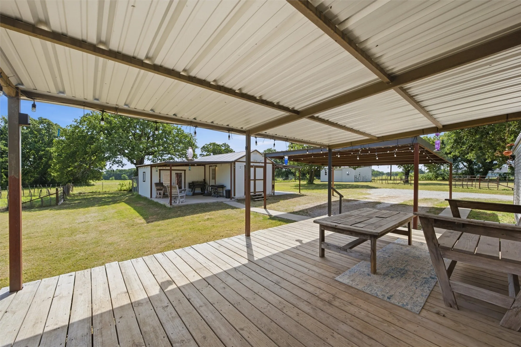 Expansive covered deck with light wood-finish flooring and a corrugated metal roof