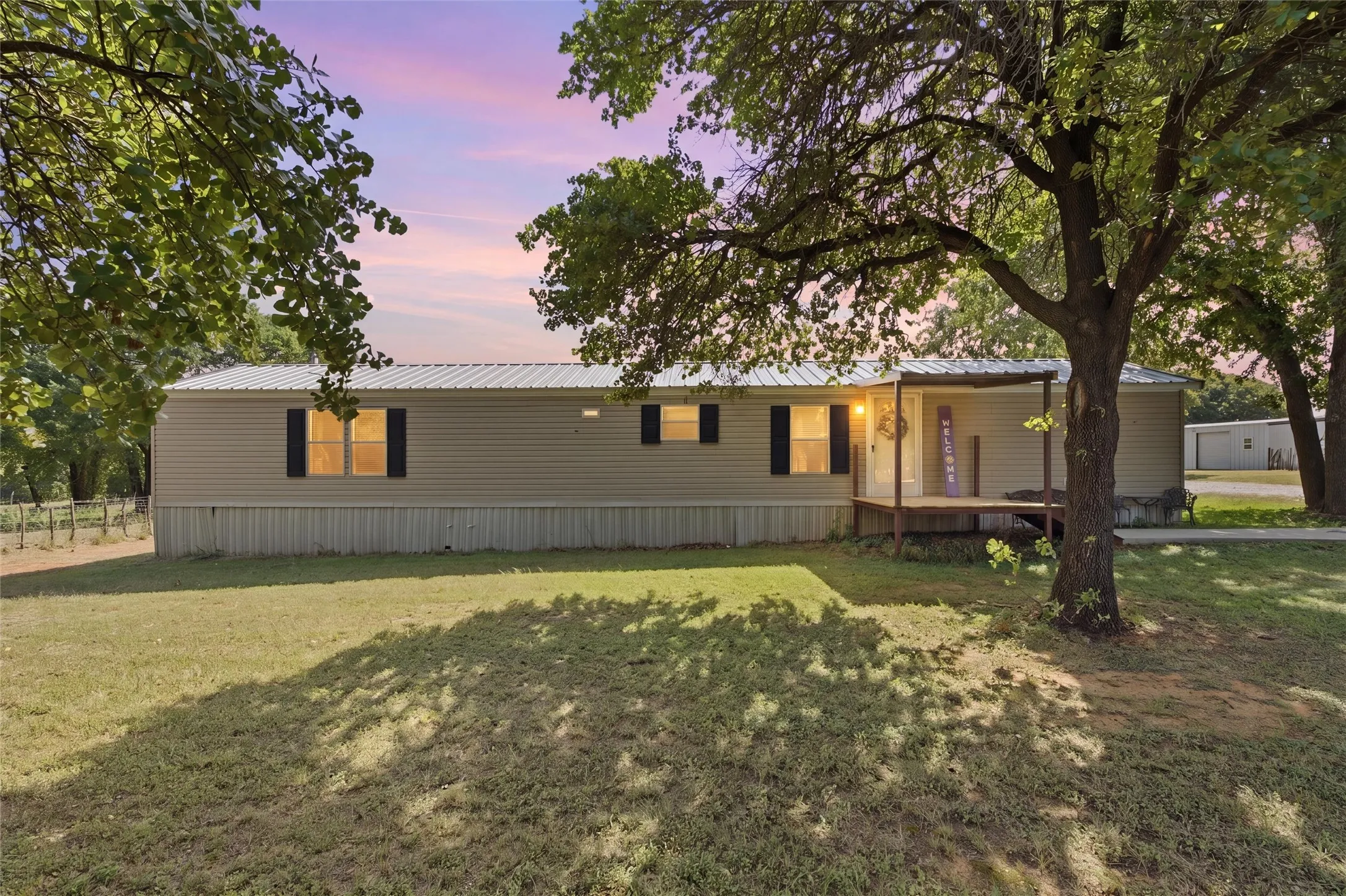 Single-story residence featuring light-colored siding, a metal roof, and dark window shutters