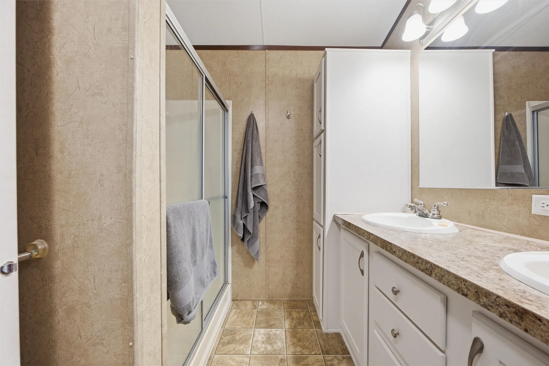 Bathroom featuring a dual-sink vanity with white cabinetry and a patterned countertop