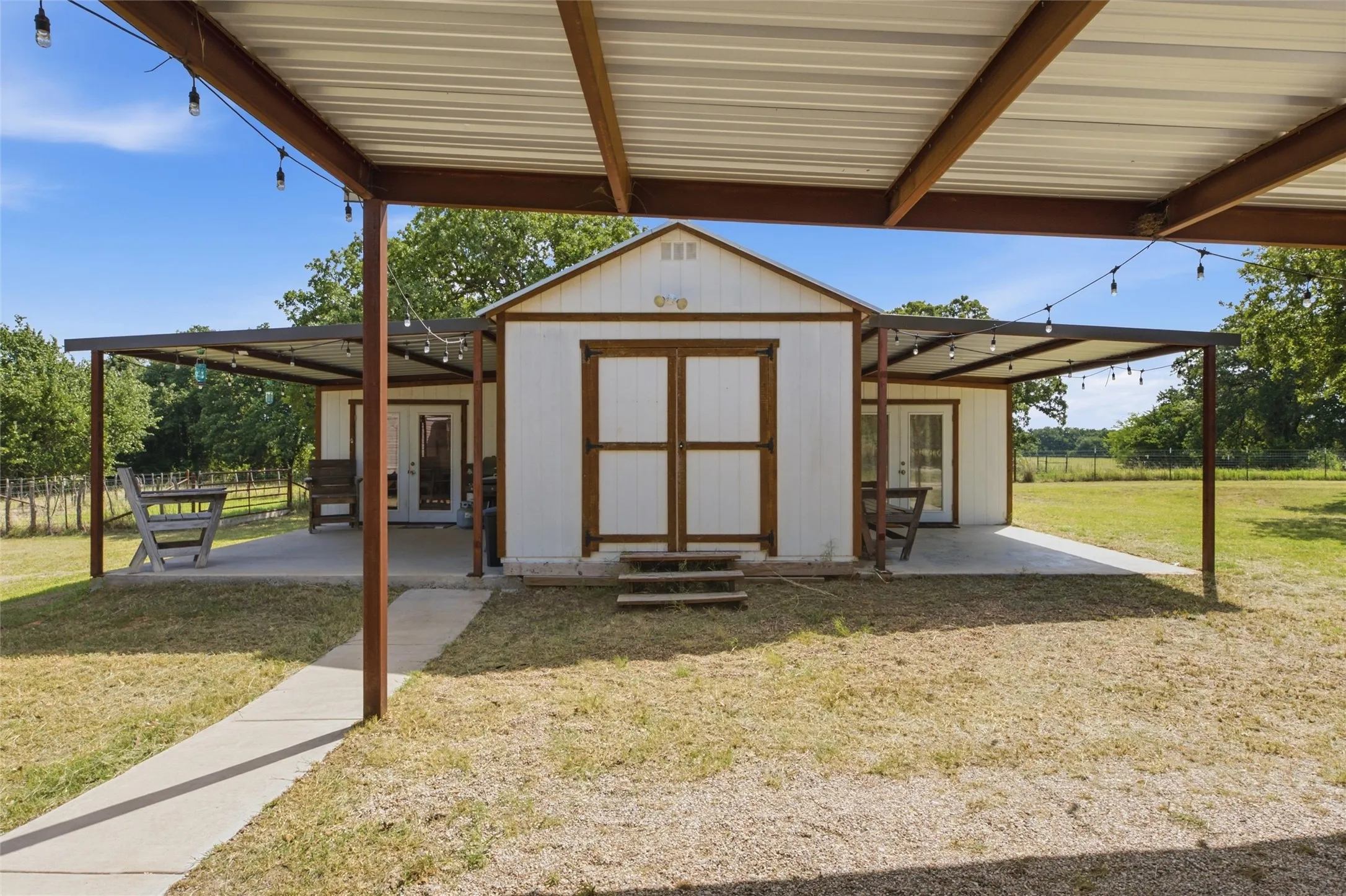 White-sided outbuilding featuring a central gable and wood-finish double doors