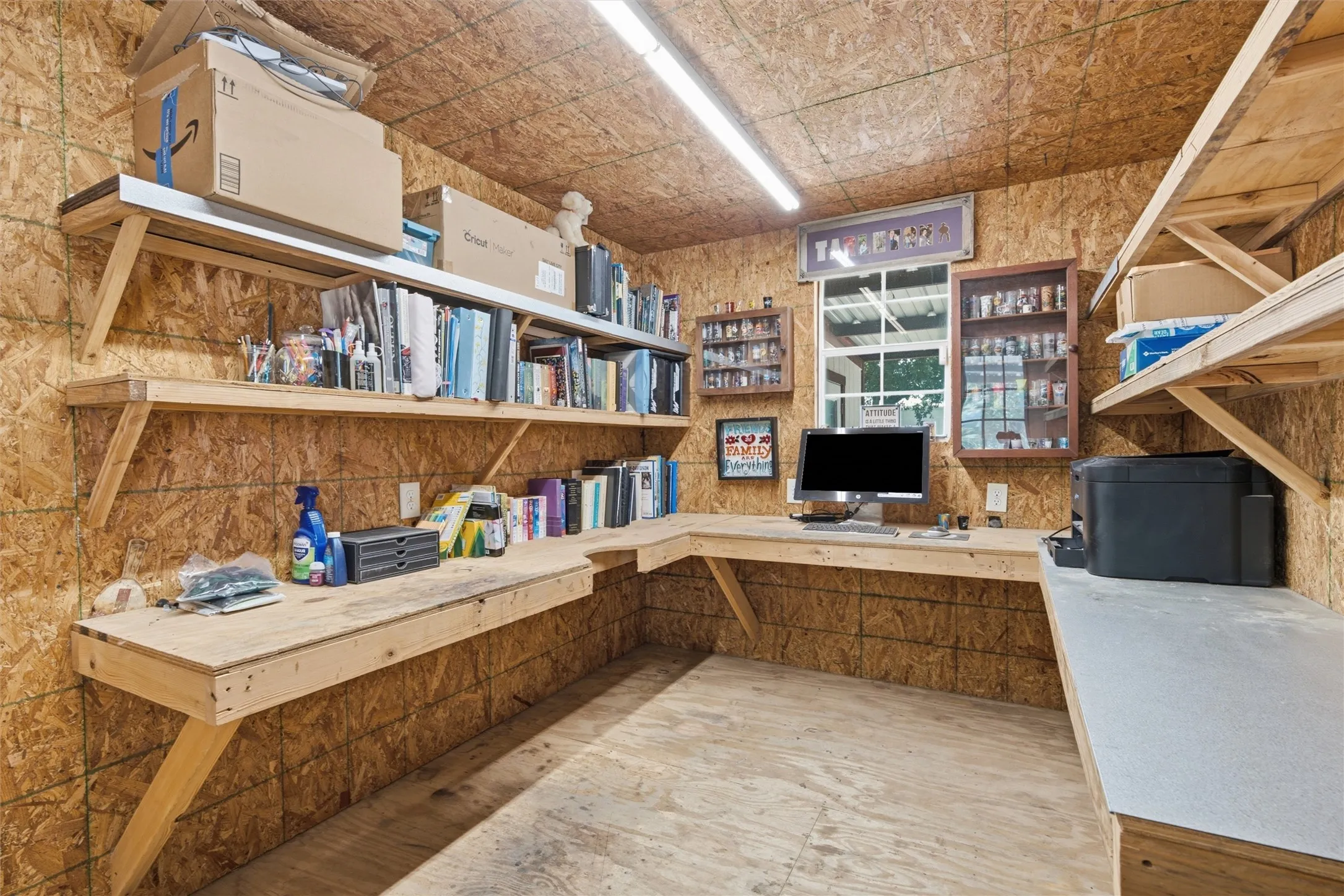 Dedicated workspace featuring extensive wraparound wood-finish countertops, exposed wood-panel walls, and integrated shelving systems